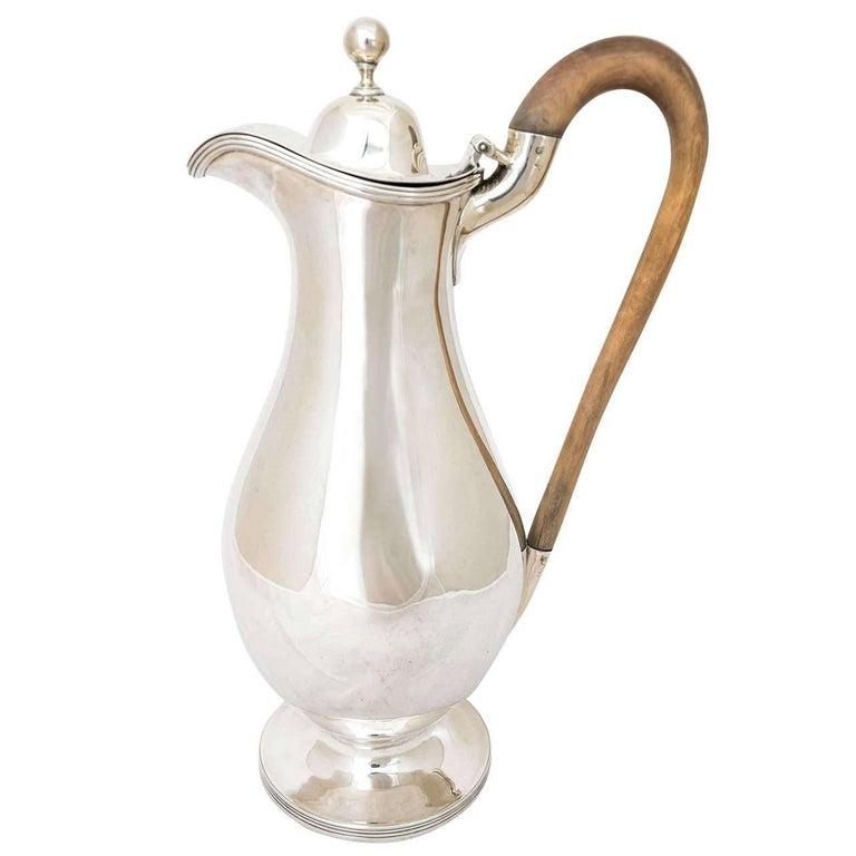 Esta hermosa y elegante jarra inglesa de plata fue fabricada por la eminente firma londinense de platería Charles Stuart Harris en 1890. El estilo es neoclásico y la altura hasta la parte superior del mango de madera es de 29 cm.
