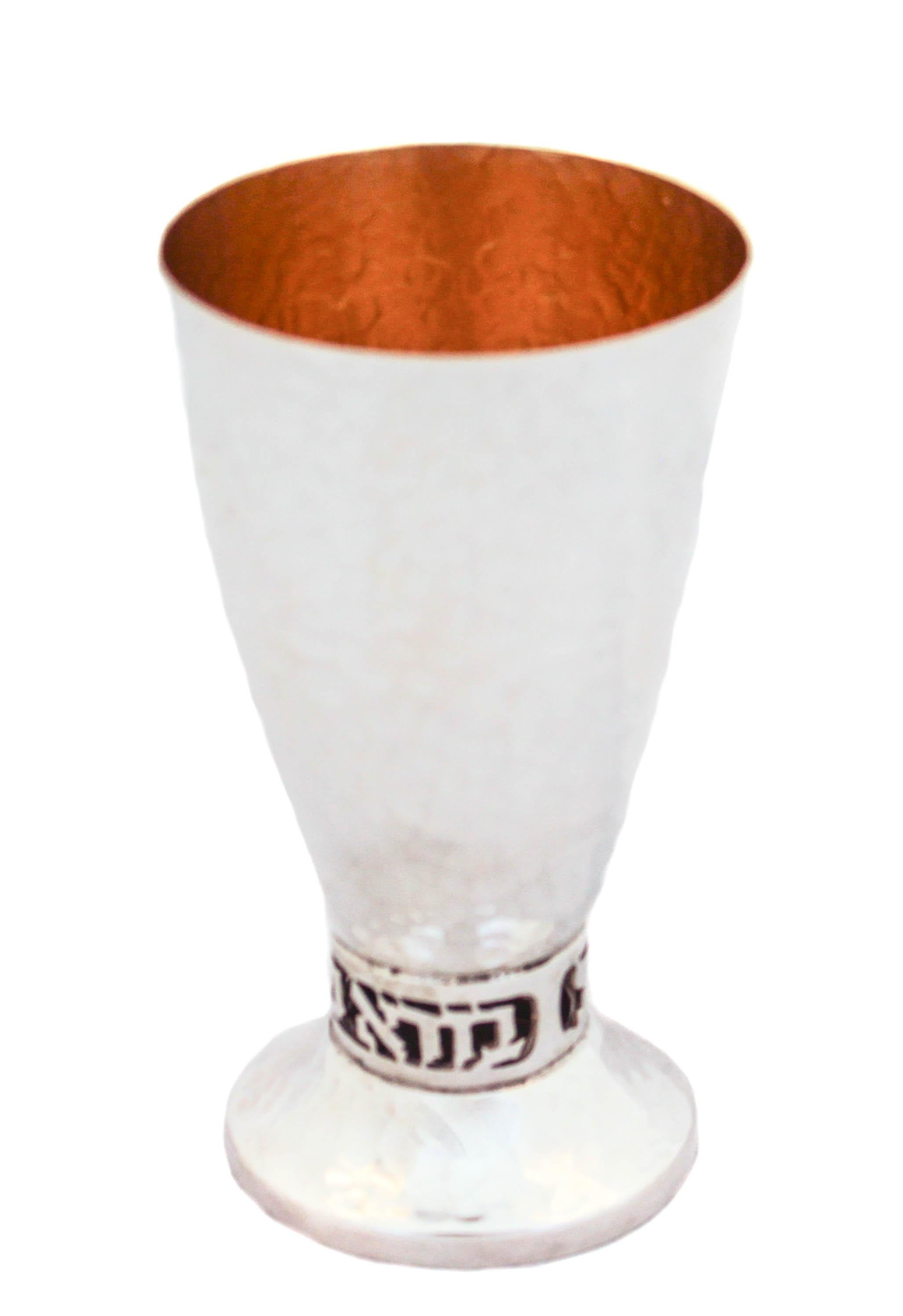 Being offered is a new sterling silver Kiddush cup made in Israel. It is hand hammered and has a gold-wash finish on the inside. Between the cup and base the Hebrew words “borei pre hagefen” (“creator of the grape” are cutout of the silver. The