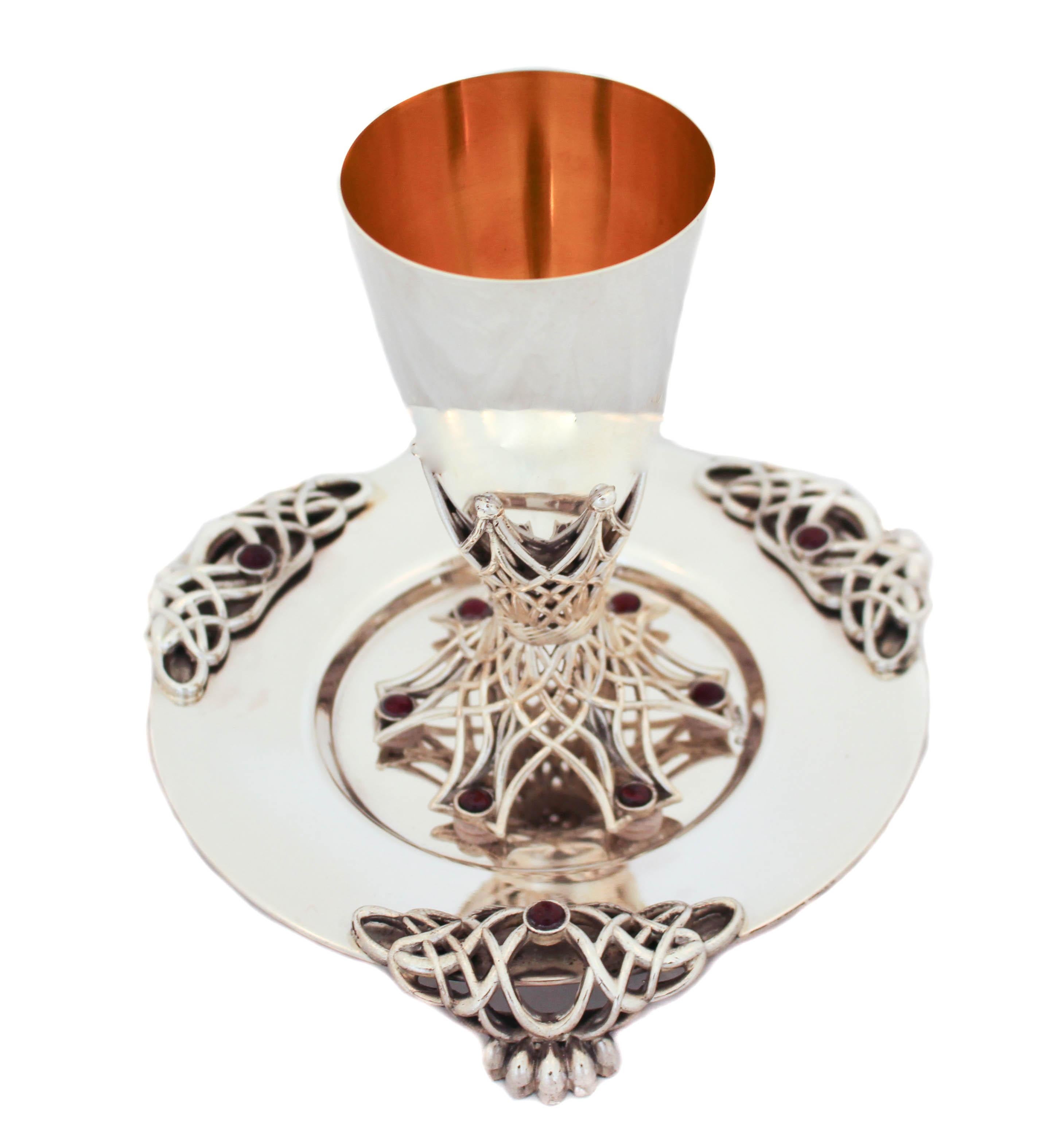 This gorgeous sterling silver Kiddush cup and plate are made in Israel. The cup has six garnet stones around the base; one stone per leg. The plate has the same design as the cup with a and larger stone in each of the feet. It’s an interesting mix