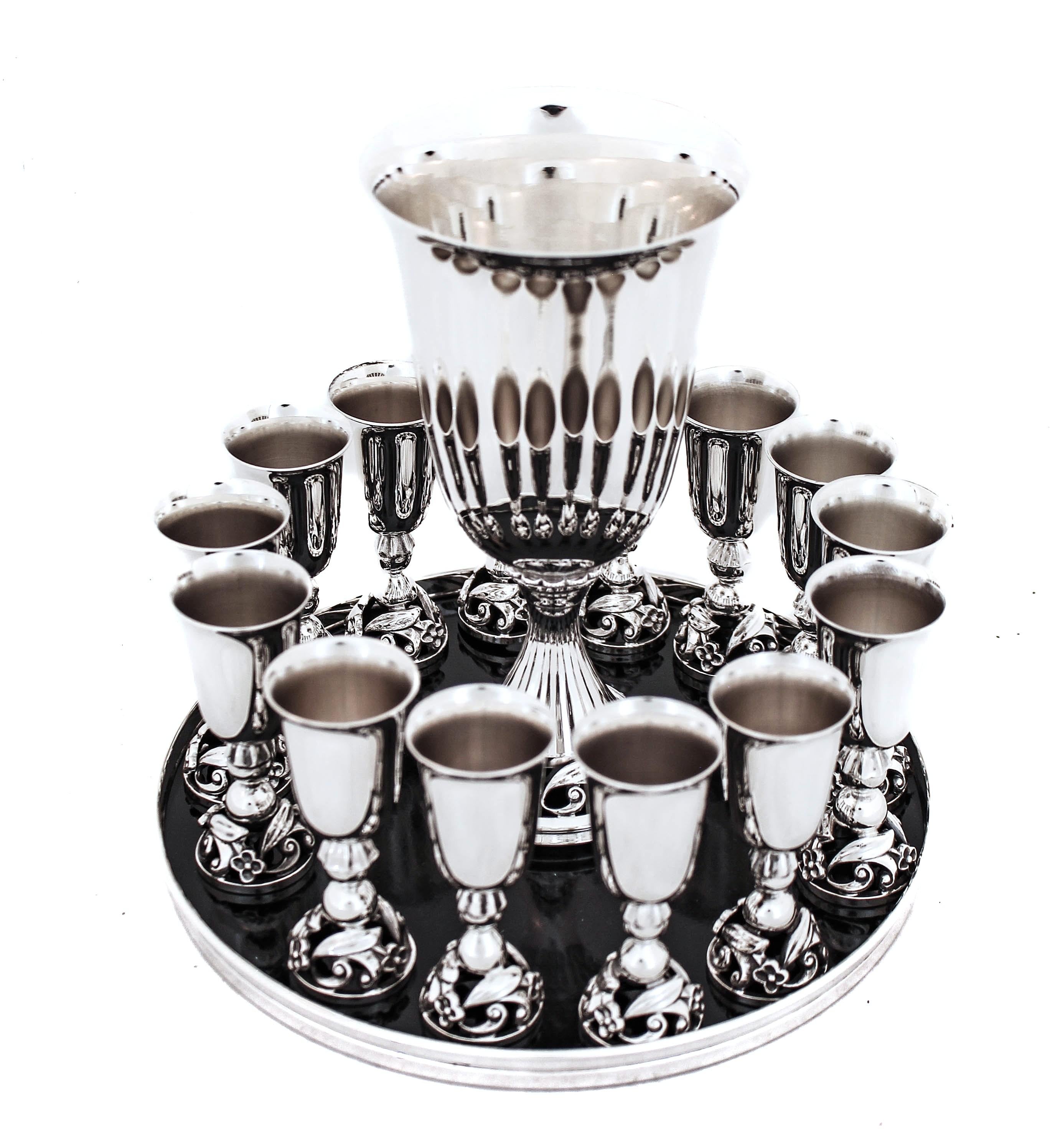 Se ofrece un juego de licor (vino) de plata de ley: 14 licores, 1 copa grande y una bandeja para servir.  Es un conjunto elegante con el motivo Art Déco alrededor de la base de cada pieza.  Todas las piezas encajan cómodamente en la bandeja,