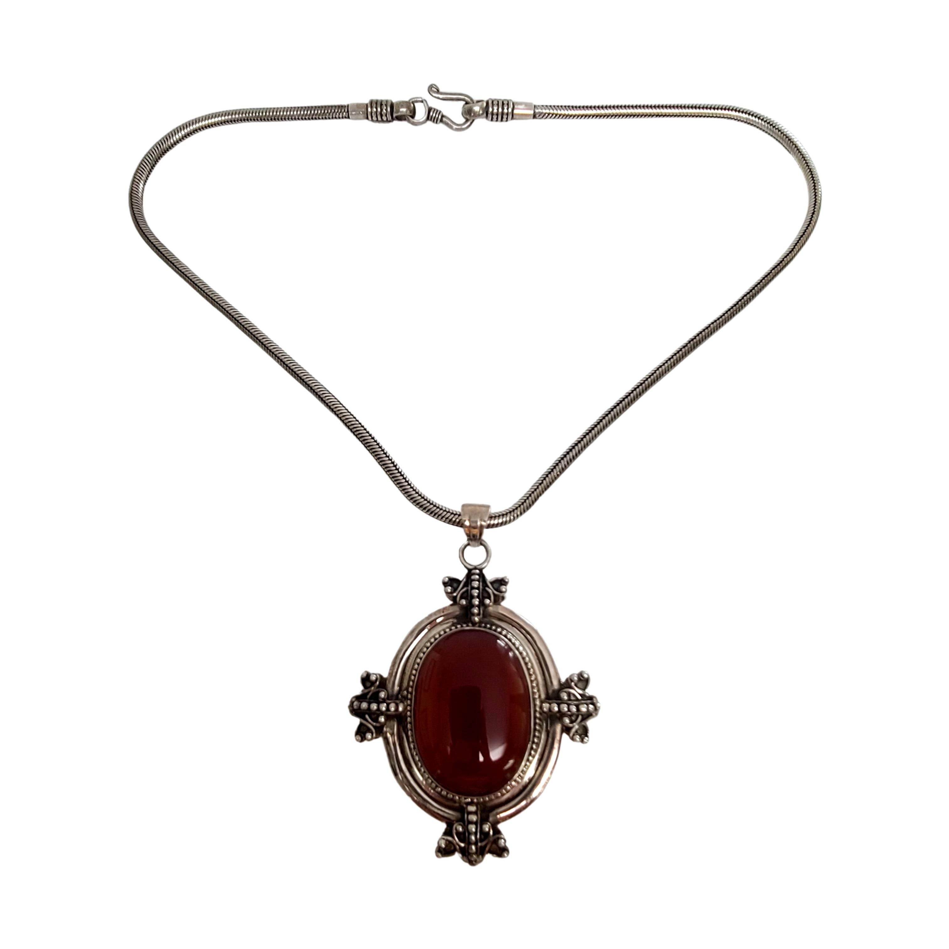 Sterling silver carnelian pendant necklace on a snake chain.

A substantial large oval carnelian pendant featuring an oval carnelian with a beaded design accents. Snake chain with hook closure.

Chain measures approx 18