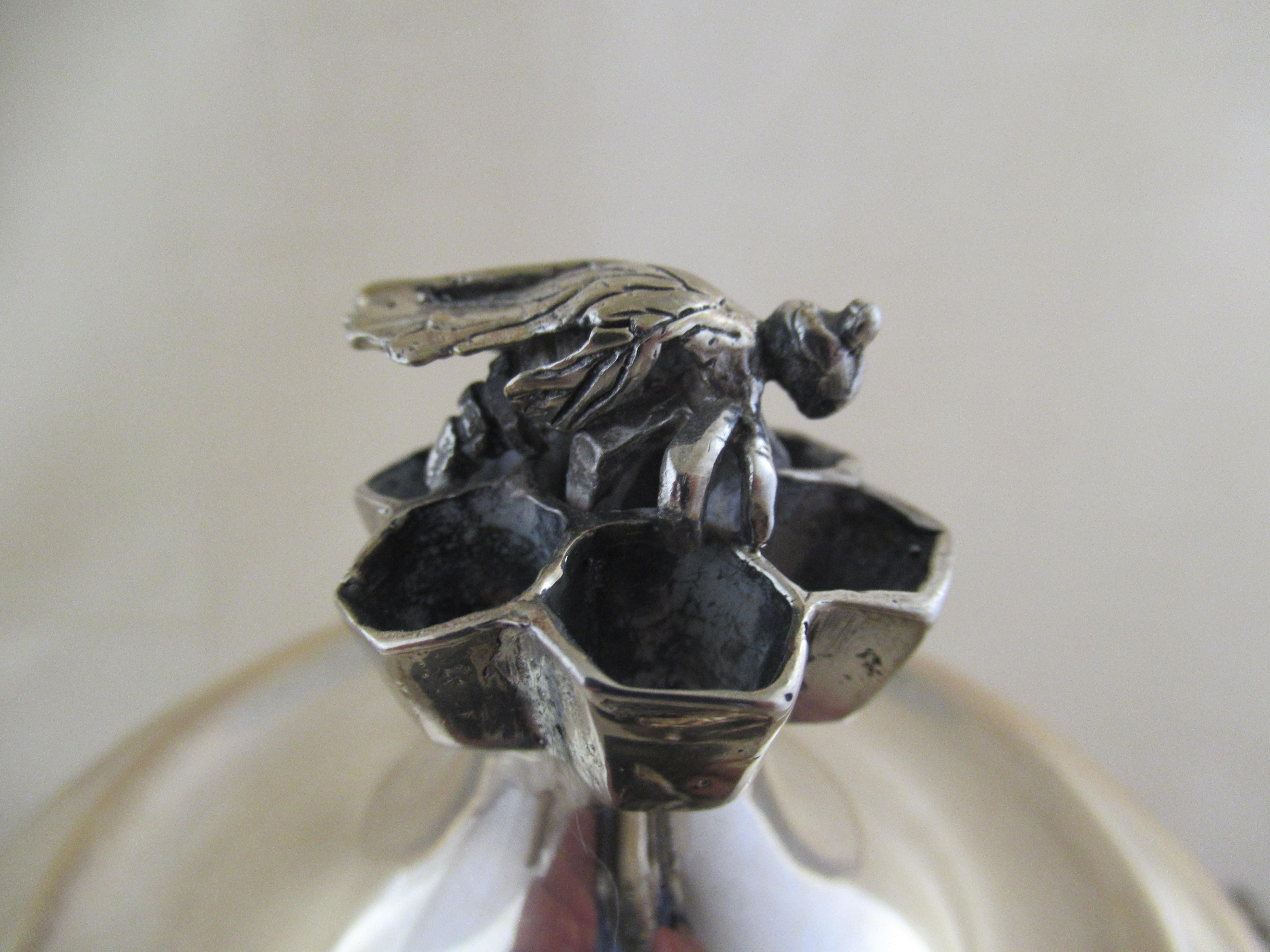 Sterling Silver LIDDED HONEY POT Made in Israel

A delightful honey pot decorated with four bees and a piece of honey comb.
The baluster shaped base has two bees - one on each side. They are a bit small for handles, but they will prevent the pot