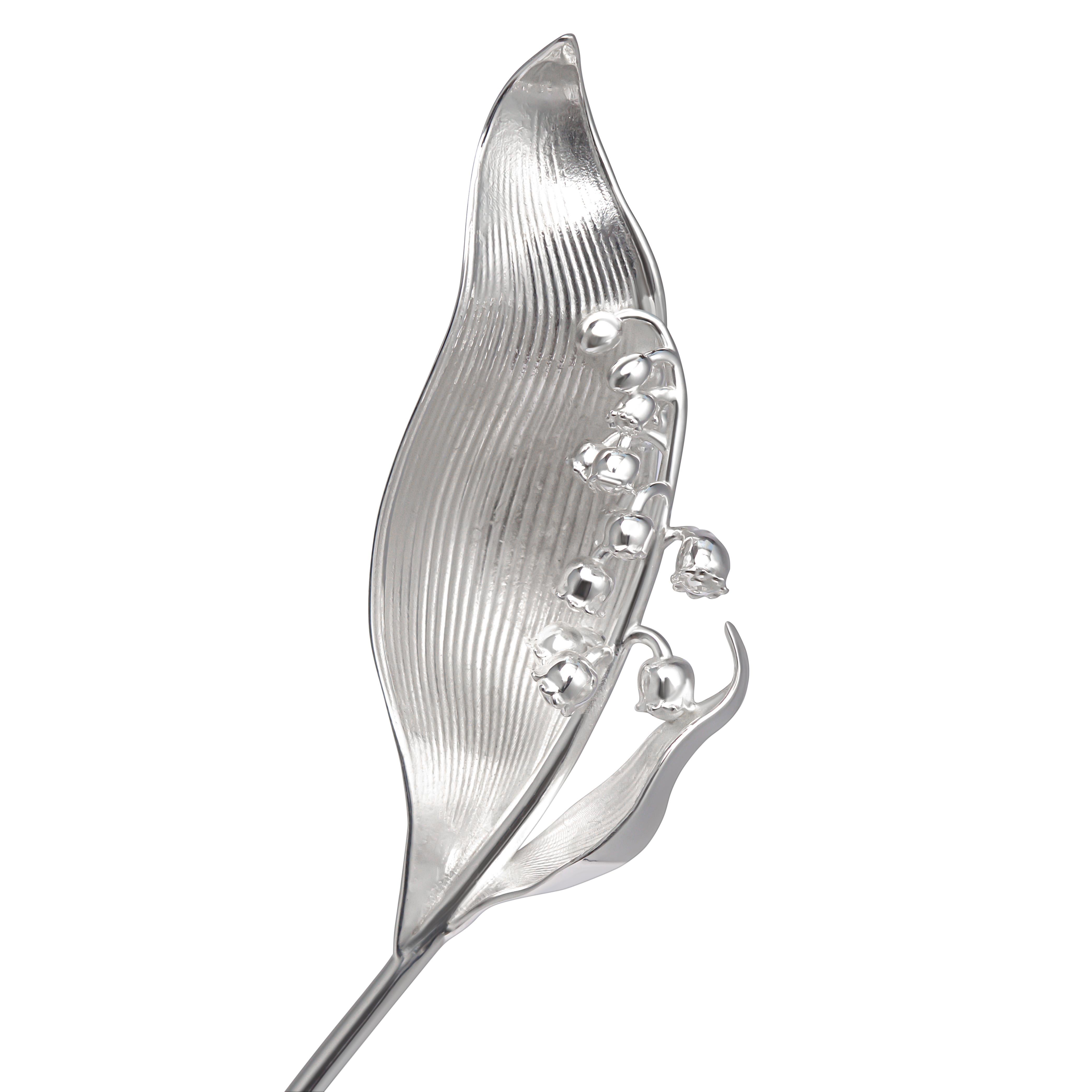 Questo cucchiaio scultoreo è realizzato a mano in argento sterling e si ispira alla forma delicata del fiore del mughetto. Il manico si curva graziosamente in una foglia scolpita, con linee sottili incise sulla superficie e sette boccioli in fiore