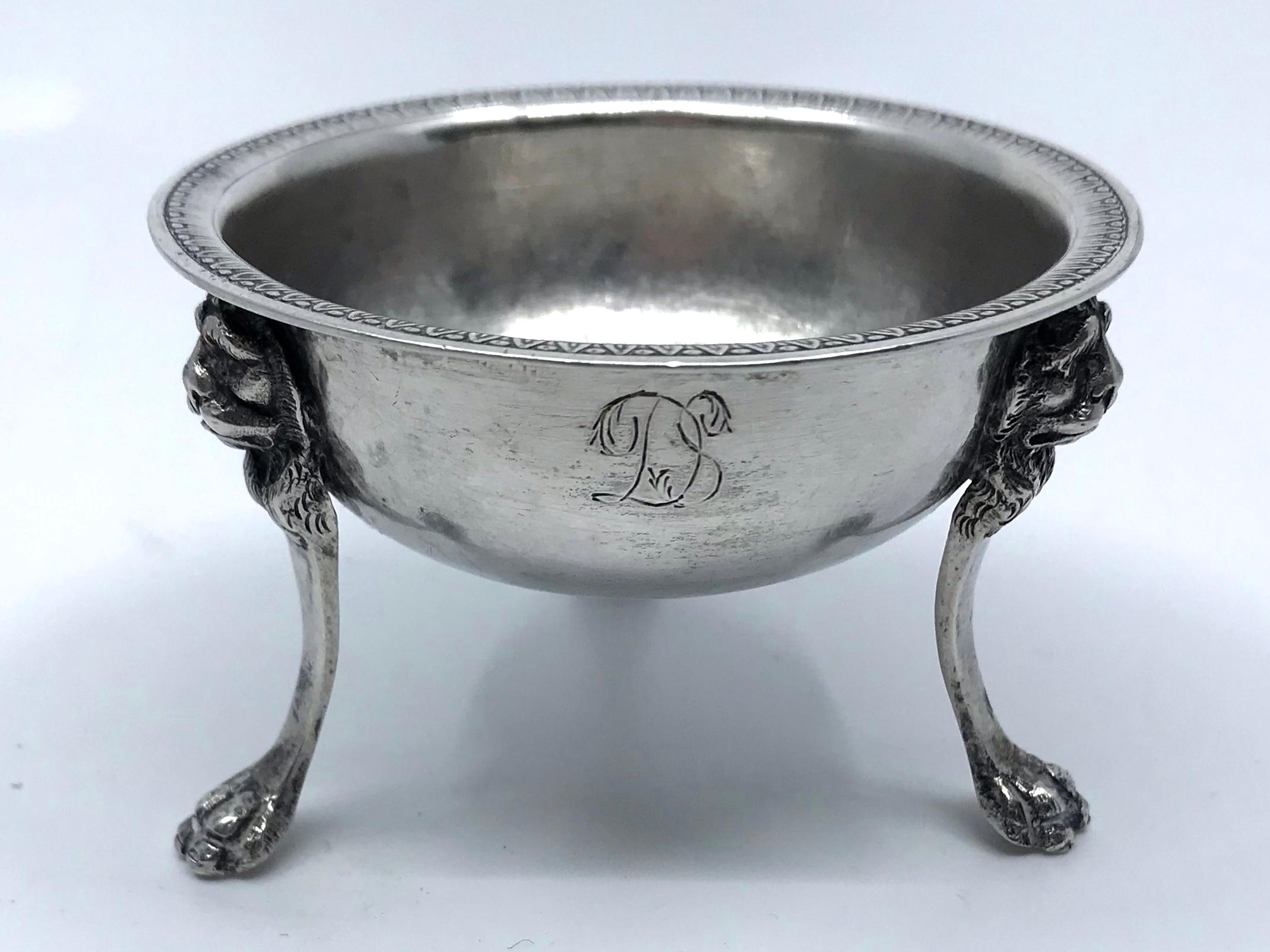 Sterling silver lions' head salt. Neapolitan silver salt / bud vase of circular form with reed and bead rim bordering silver bowl supported on tripartite base with lion head masks on incurving legs above paw feet. Engraved 