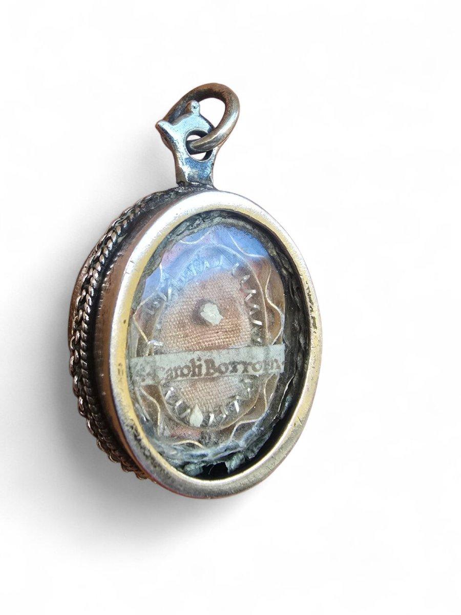 Élégant reliquaire du XVIIIe siècle en argent massif, finement gravé à la main, avec une décoration ornementale typique de l'art religieux baroque. Sa forme ovale présente des détails floraux et symboliques qui reflètent la dévotion et le travail