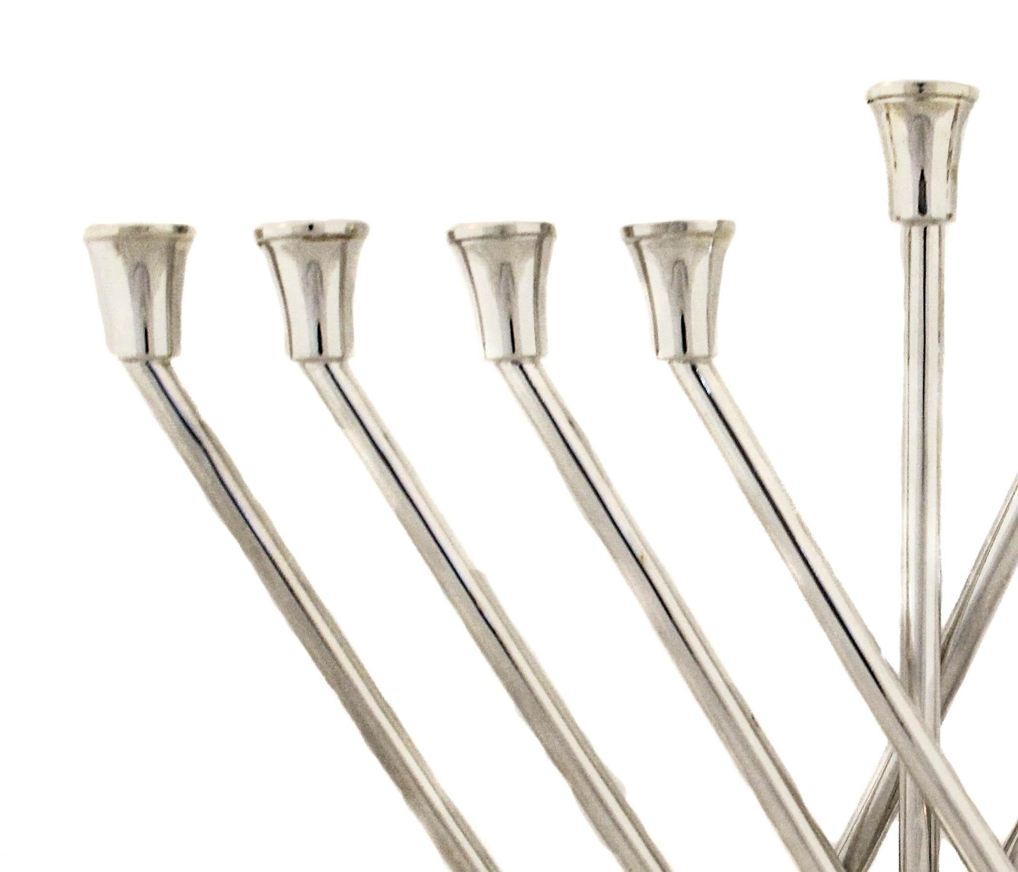 Viene offerta una nuova menorah in argento sterling dal design moderno.  Seduti su una base rettangolare con una sfera alla base di ogni ramo, i bracci si alzano e si incrociano tra loro.  Una rivisitazione contemporanea di una tradizione millenaria.
