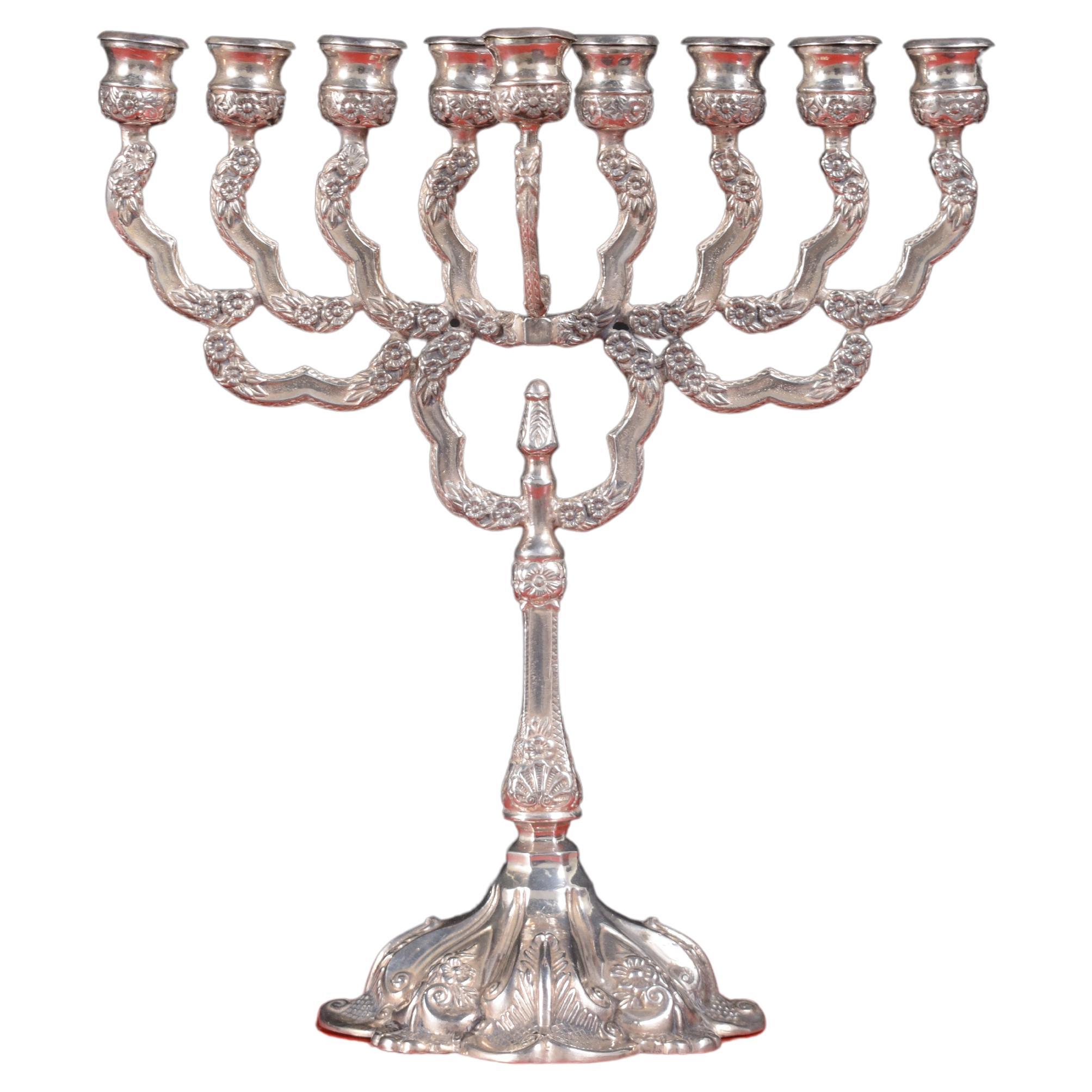 Celebrate Hanukkah with elegance and tradition with our Sterling Silver Menorah from Israel. This regal and rich-looking menorah boasts a distinguished design, featuring a square base that stands securely on four feet. The intricate detailing