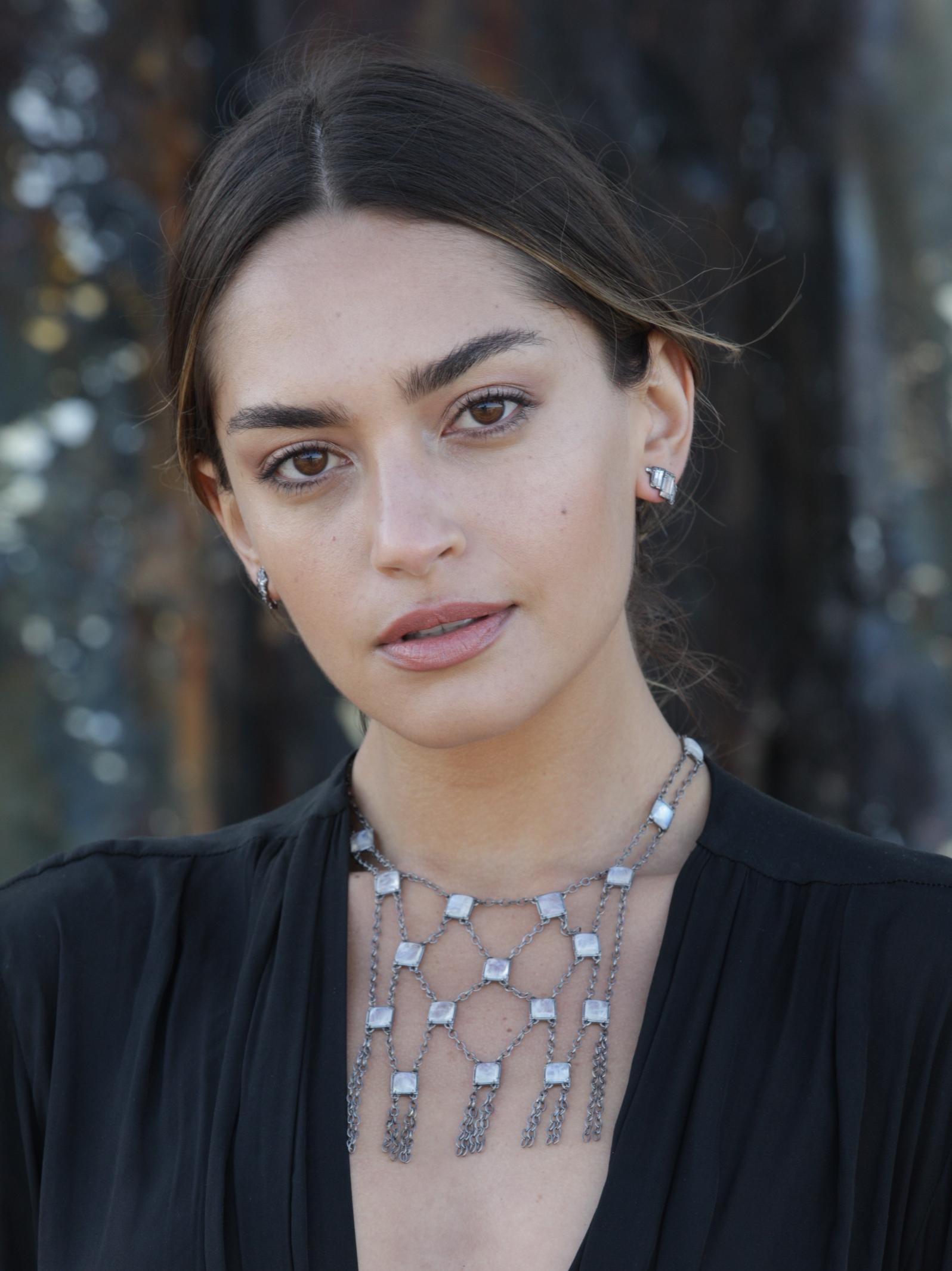 The glowing blue moonstone on open work sterling silver  mesh chain is designed strategically to function casually or as a bold standout.  
Whether on the skin or over a garment, this alluring yellow gold bib necklace is a versatile layer added to a