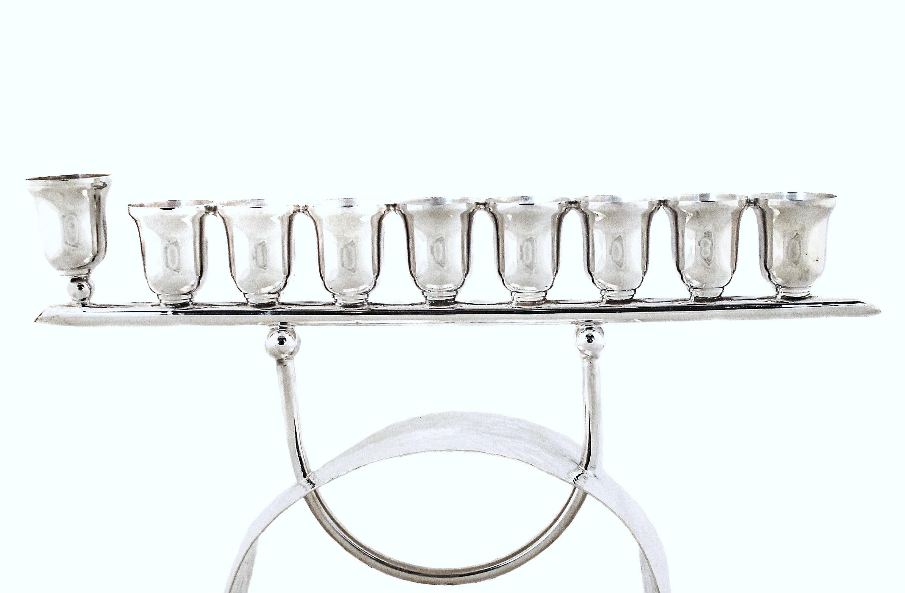 Un diseño moderno para una tradición milenaria; ¡esta menorá de plata de ley es contemporánea y elegante!  Una base curvada martillada sostiene las ocho luces que están conectadas por una pieza en forma de U con bolas, similar a las dos piezas del