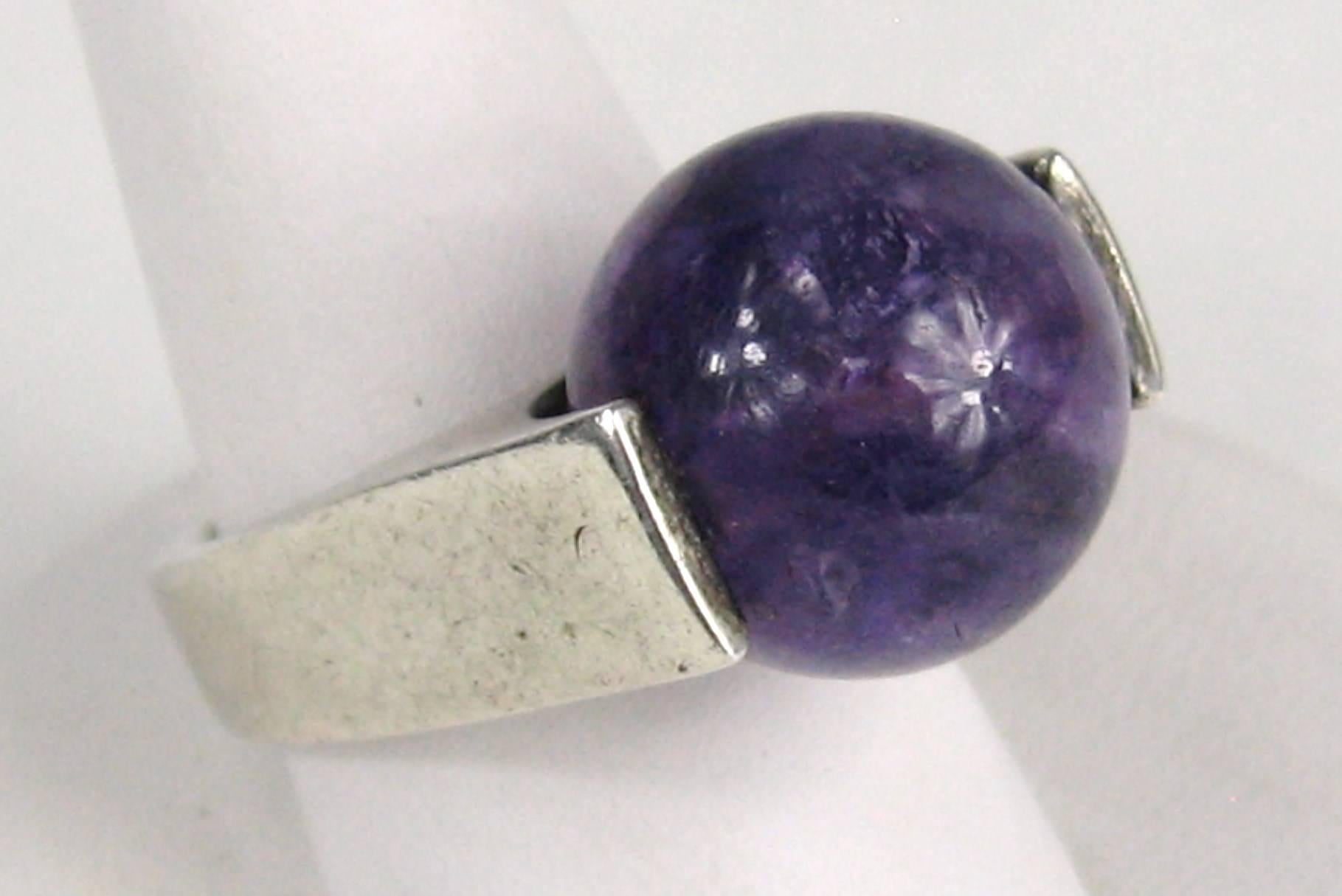 Huge round Amethyst stone sitting in a fairly heavy sterling setting. Clean lines, very Modernist. This is a very cool ring. Size is 6 and can be sized by a  jeweler. Patina as found, unless you request a cleaning. This is out of a massive