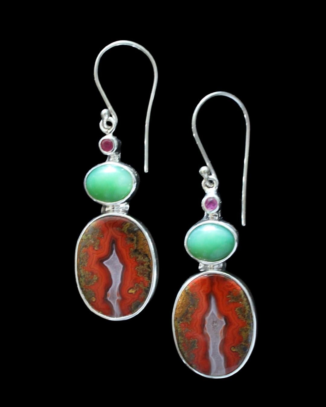 These earrings showcase a pair of oval cut Moroccan Seam Agates. The stones are complimented by an oval cut jade with faceted ruby accent stones are set in sterling silver. Seam Agates, a variety of plume or flame agate, is also known as Vein