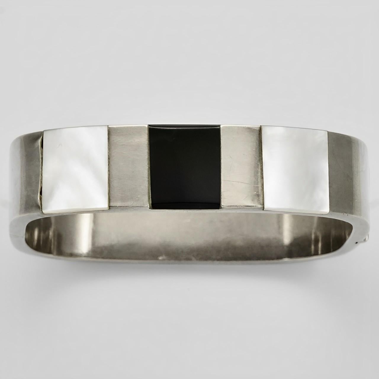 Wonderful sterling silver bangle bracelet, set with mother of pearl and onyx. It is rectangular, the inside measurements are 5.8 cm / 2.2 inches by 5.4 cm / 2.1 inches, and the width is 1.45 / .5 inch. There is scratching as expected, and two small