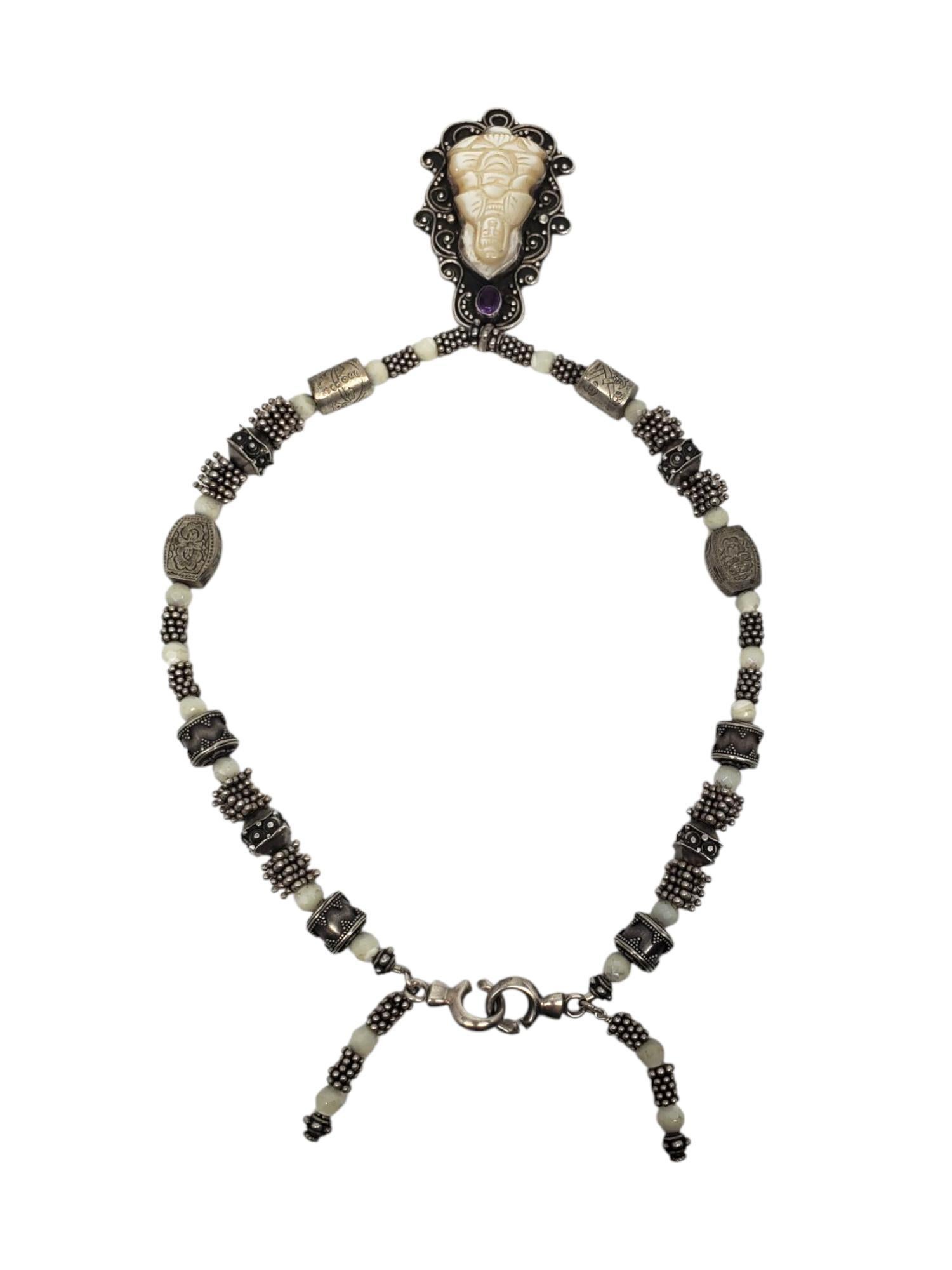 Collana con ciondolo Buddha in argento 925 e madreperla 

Questa collana spirituale unica presenta un Buddha in madreperla (45 mm x 30 mm) con una pietra d'accento ametista e una catena con perline a barile e a tamburo in argento sterling con
una