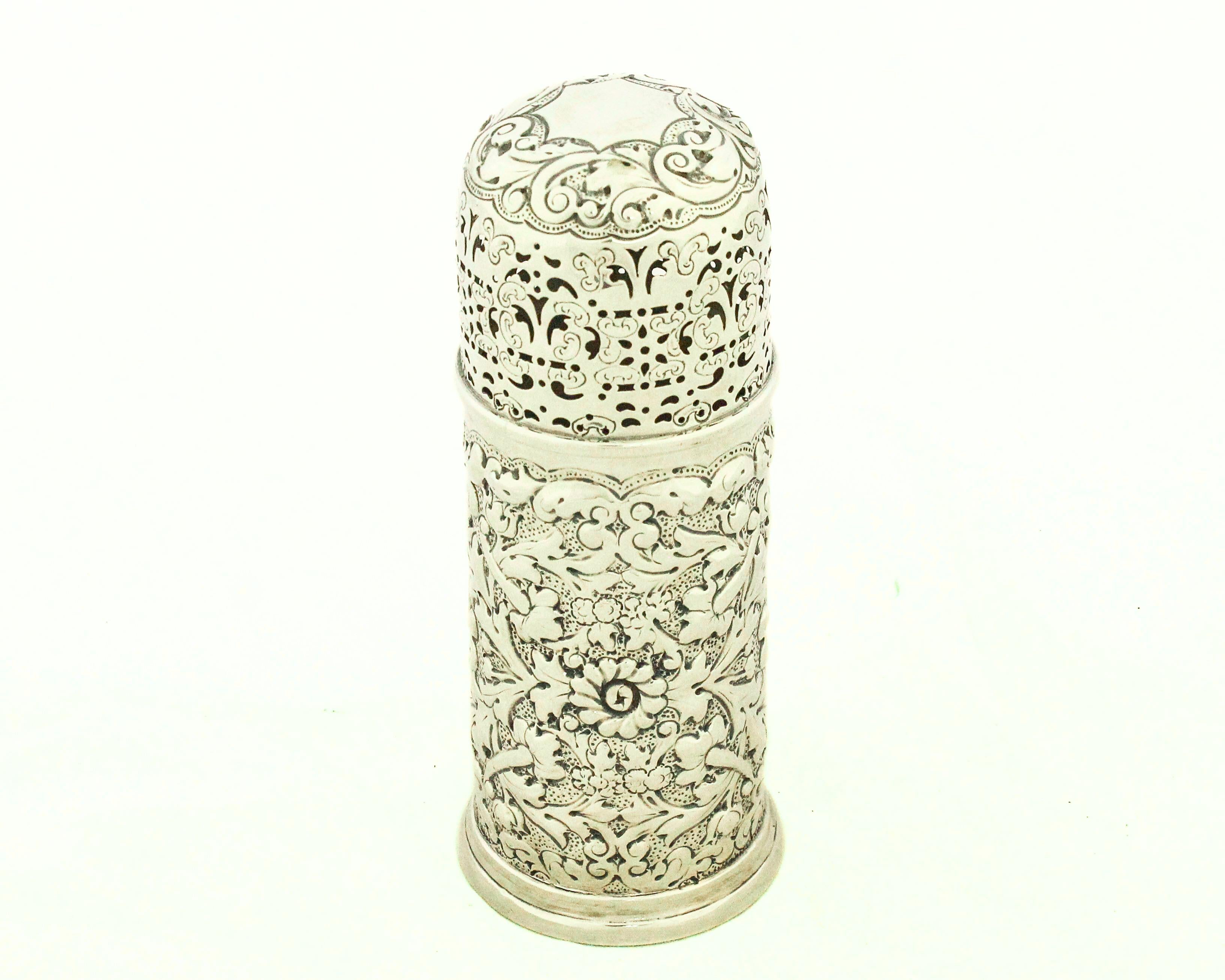 Questa raffinata muffinatrice (o zuccheriera) vittoriana in argento sterling mostra i ricchi ornamenti repoussé e piercing caratteristici dell'argento inglese della metà del XIX secolo. Il corpo cilindrico è decorato in modo elaborato con volute