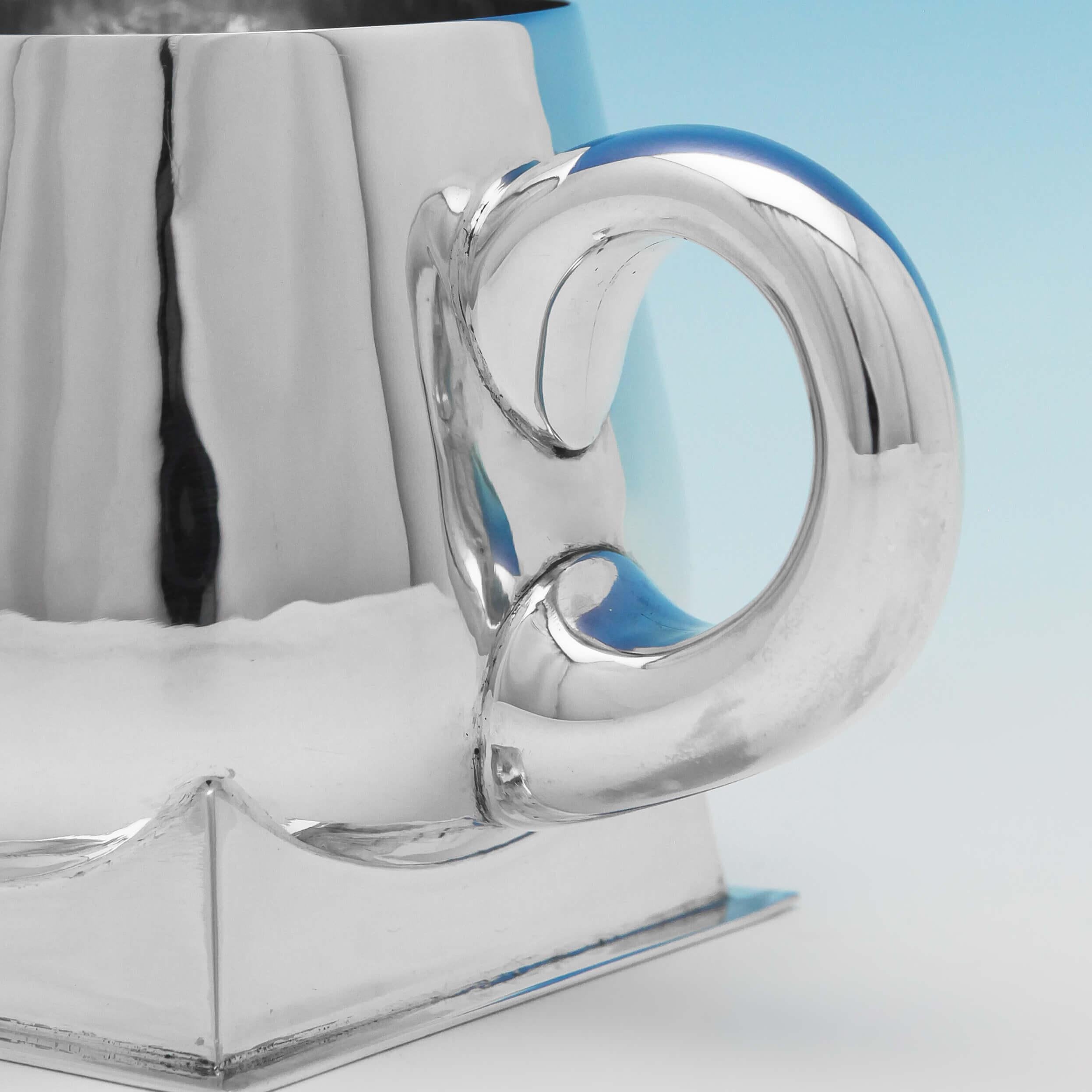 Hallmarked in London in 1936 by Charles Boyton, this unusual sterling silver mug has both Arts & Crafts and Art Deco influences. Finely crafted, the rounded hand-hammered body stands on a geometric base with a simple bulbous handle. Signed Charles