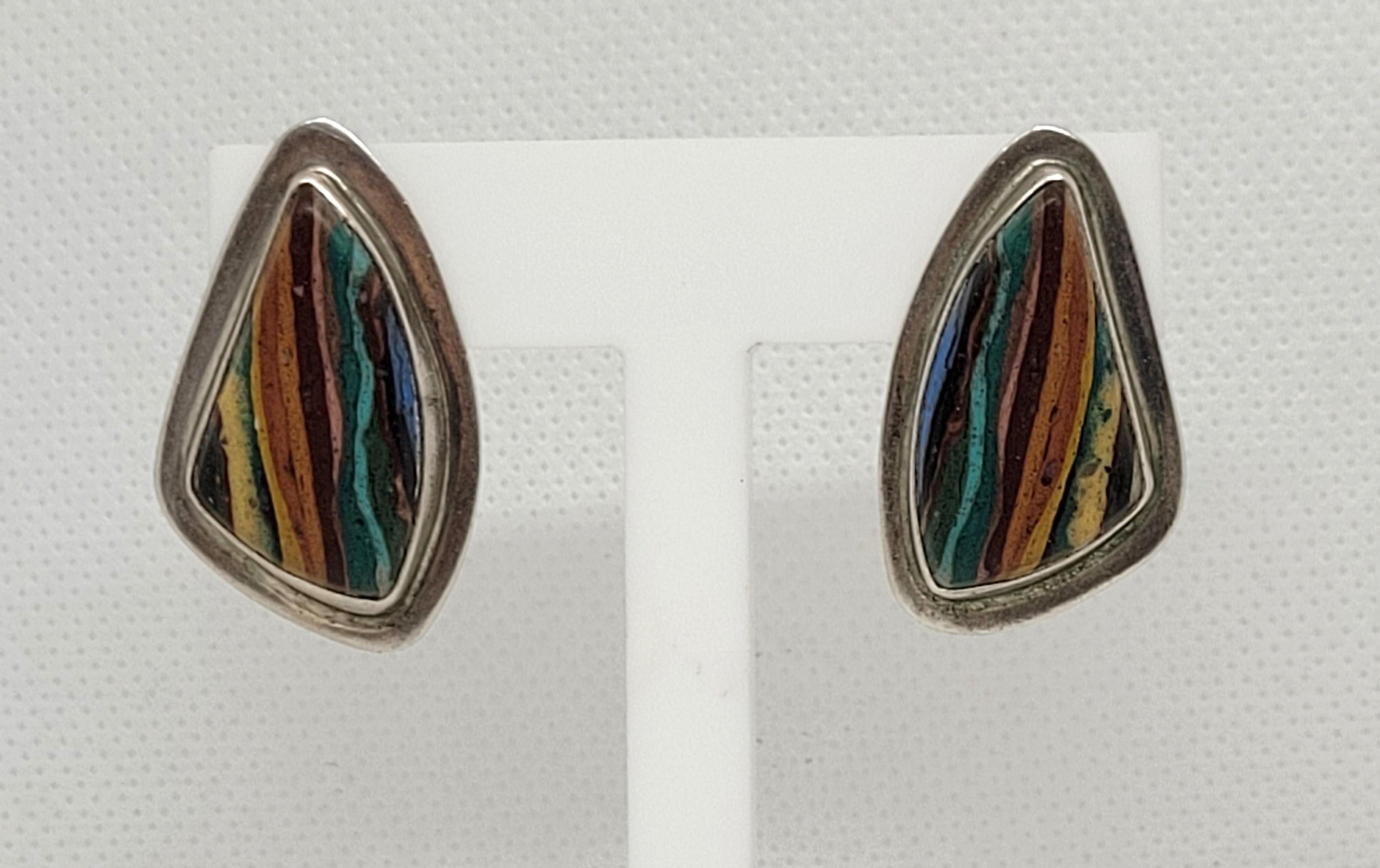 Pendientes de plata de ley con incrustación multicolor y fricción, con piedras en azul, marrón, tostado y verde. Los pendientes pesan un total de 12 gramos y miden 21 mm x 33 mm x 6 mm. Llevan la marca del diseñador y 