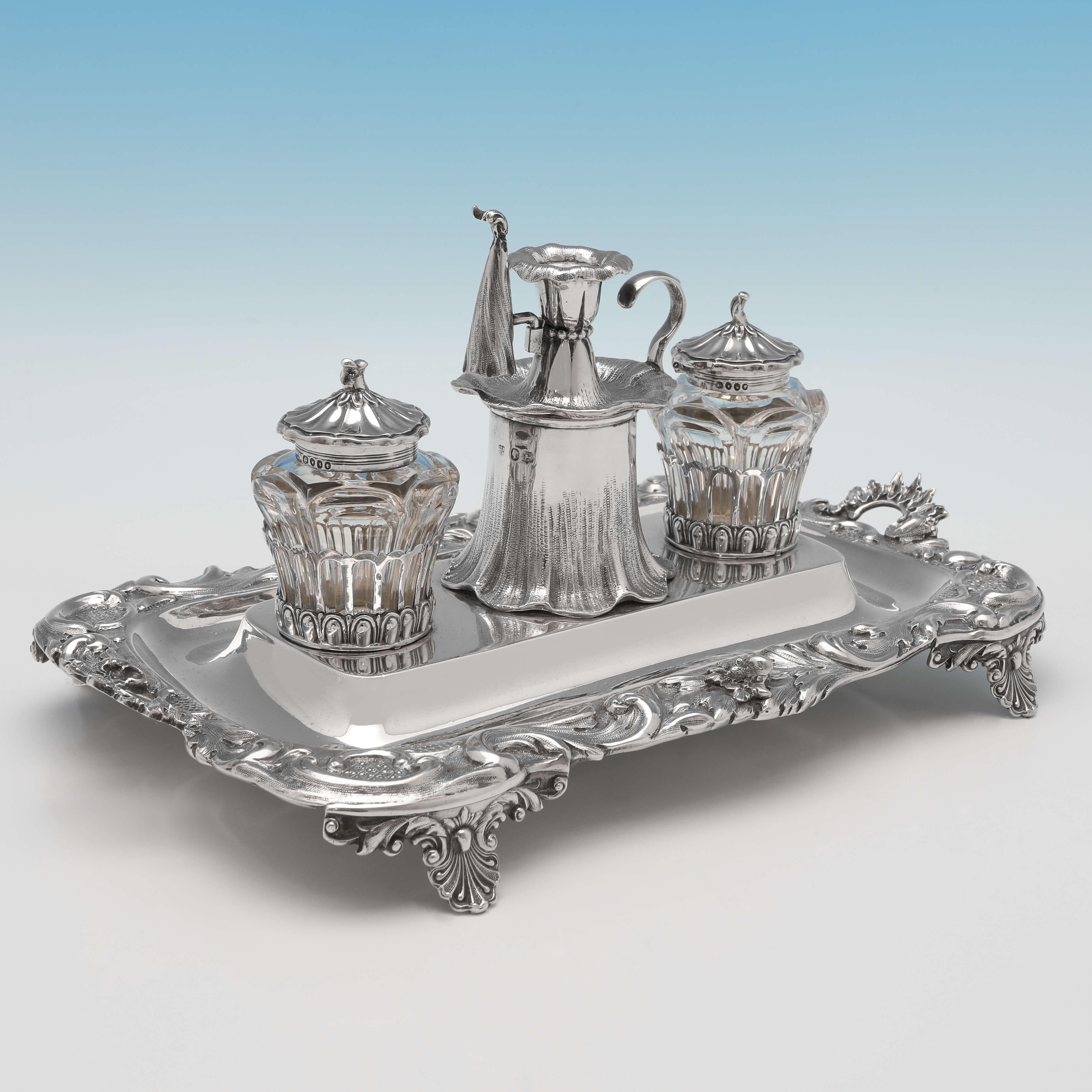 Hallmarked in London in 1846 by Charles & George Fox, this charming, Victorian, Antique Sterling Silver ink stand, features an ornate scroll border, decorative feet, and naturalistic design ink pots and taper-stick. The ink stand measures 5.5