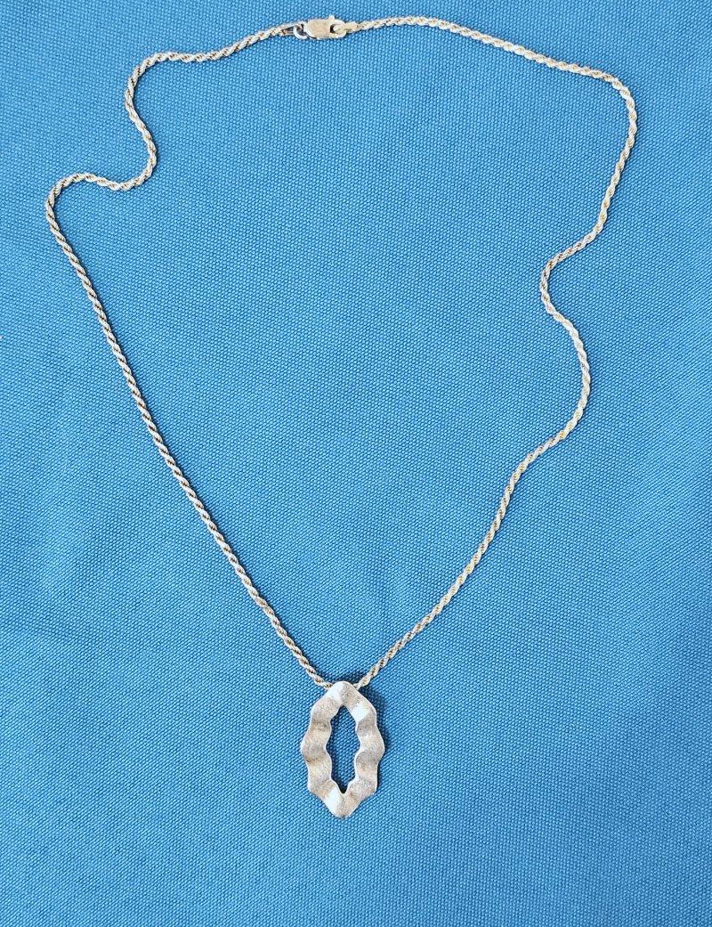 Sterling Silver Necklace with Oval Ruffled Pendant Slide.
The front of the pendant is textured; the back is smooth.  The chain is stamped. 
We could not locate a stamp on the oval slide so while it appears to be sterling, we aren't sure. 
Needs