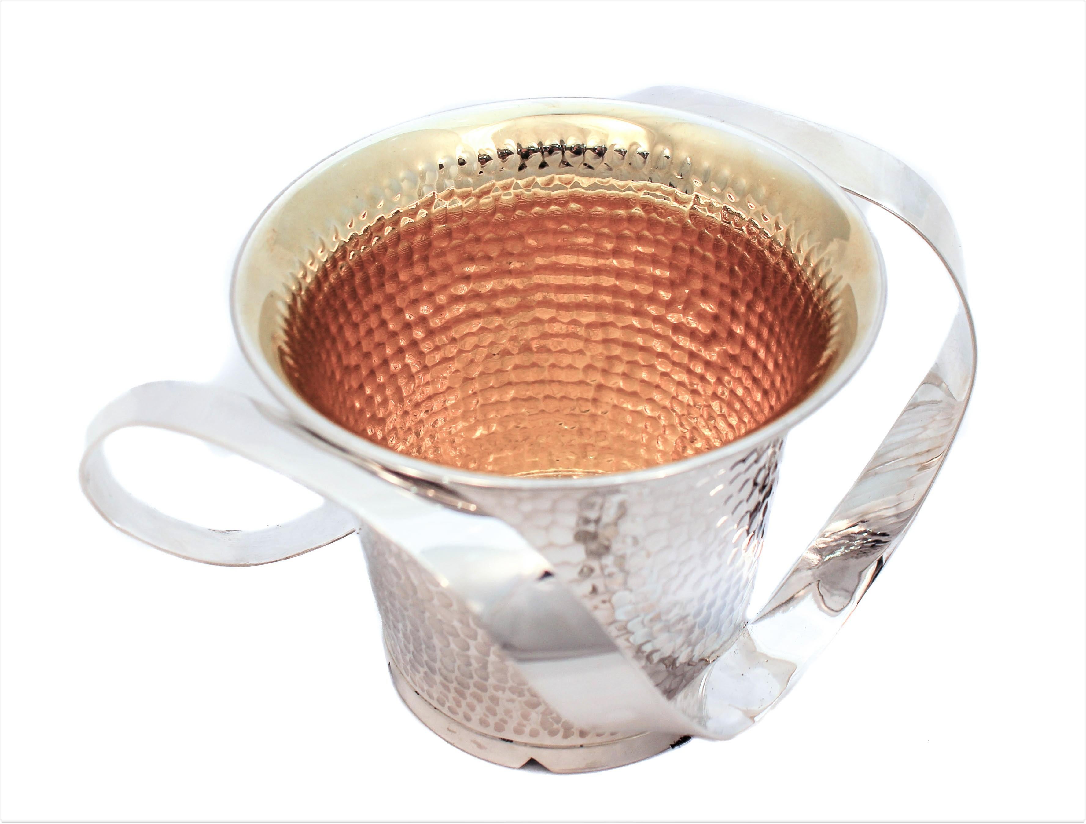 We are happy to offer you this sterling silver hammered n’tillat yadaiyim (washing cup)cup. It is hand-hammered with a modern handle. The base has six triangular cutouts that add to the modern, sleek look. Gold-washed on the inside to protect it