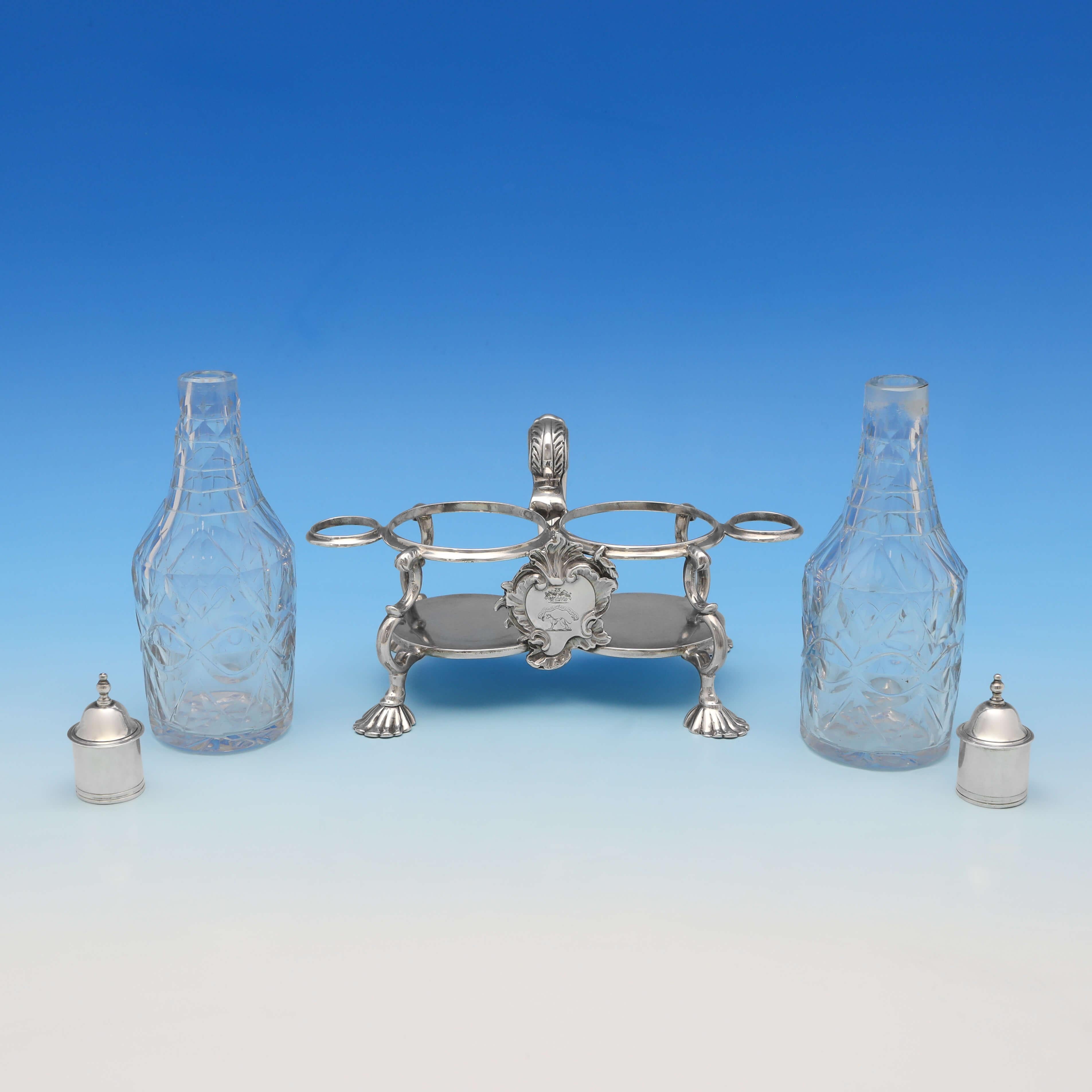 Hallmarked in London in 1751 by Samuel Wood, this striking, George II, antique sterling silver oil and vinegar set, is in the Rococo taste, and is engraved to one side with a crest. The oil and vinegar set measures 7.5