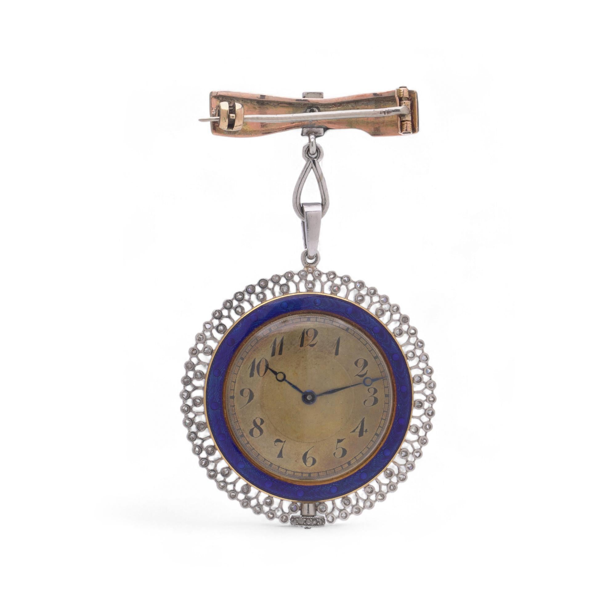 Un orologio da tasca edoardiano con ciondolo, realizzato in argento e smalto, sospeso da una spilla a fiocco. La cassa circolare è decorata sul davanti con un ricco smalto guilloché blu reale, impreziosito al centro da un motivo a grappolo di
