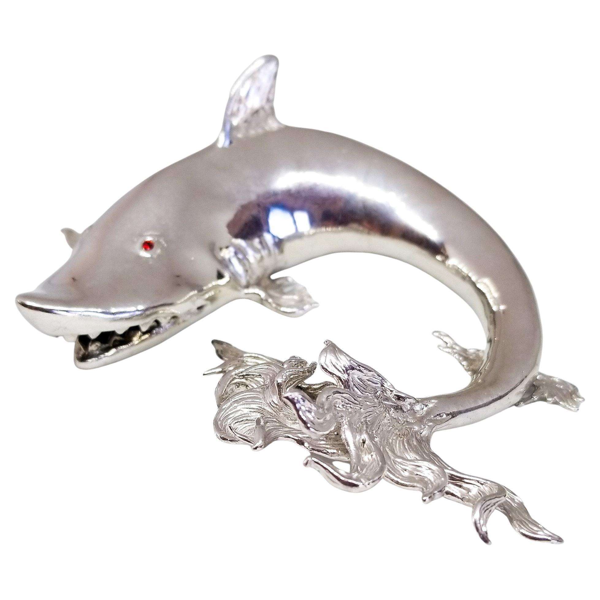 Unique.
One of a Kind Collection Piece.
Jewel Eyed Shark Figurine in Sterling Silver.
This palm sized Desk and Curio Showpiece is constructed in Highly Polished Solid Sterling Silver. Adorning the Whimsical Shark are two Brilliant Cut, Orange