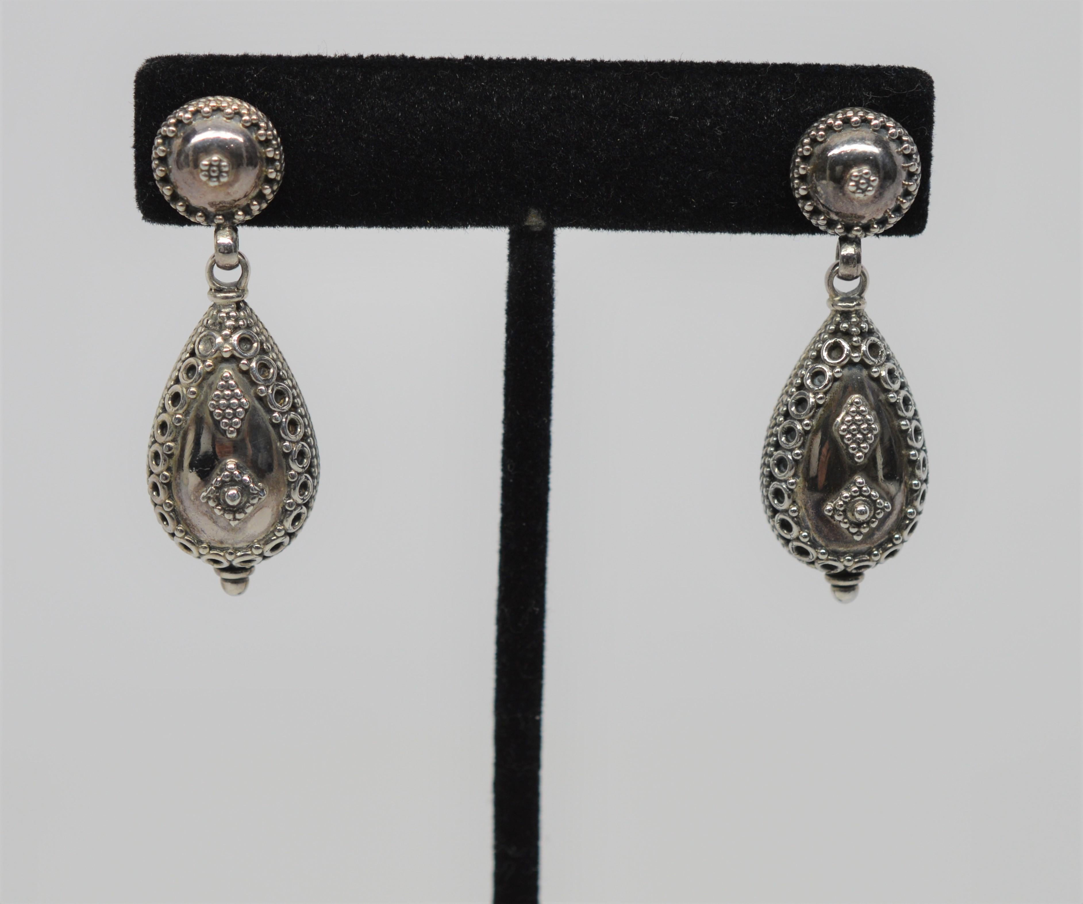 Crafted Sterling Silver from the sub-continent of India, these Tear Drop Puff Charm Dangle Earrings are adorned with ornate detail in Silver.  
Made with a push back, secured to a decorated post. The Sterling Silver Puff Charm dangles 1-1/4 inch.