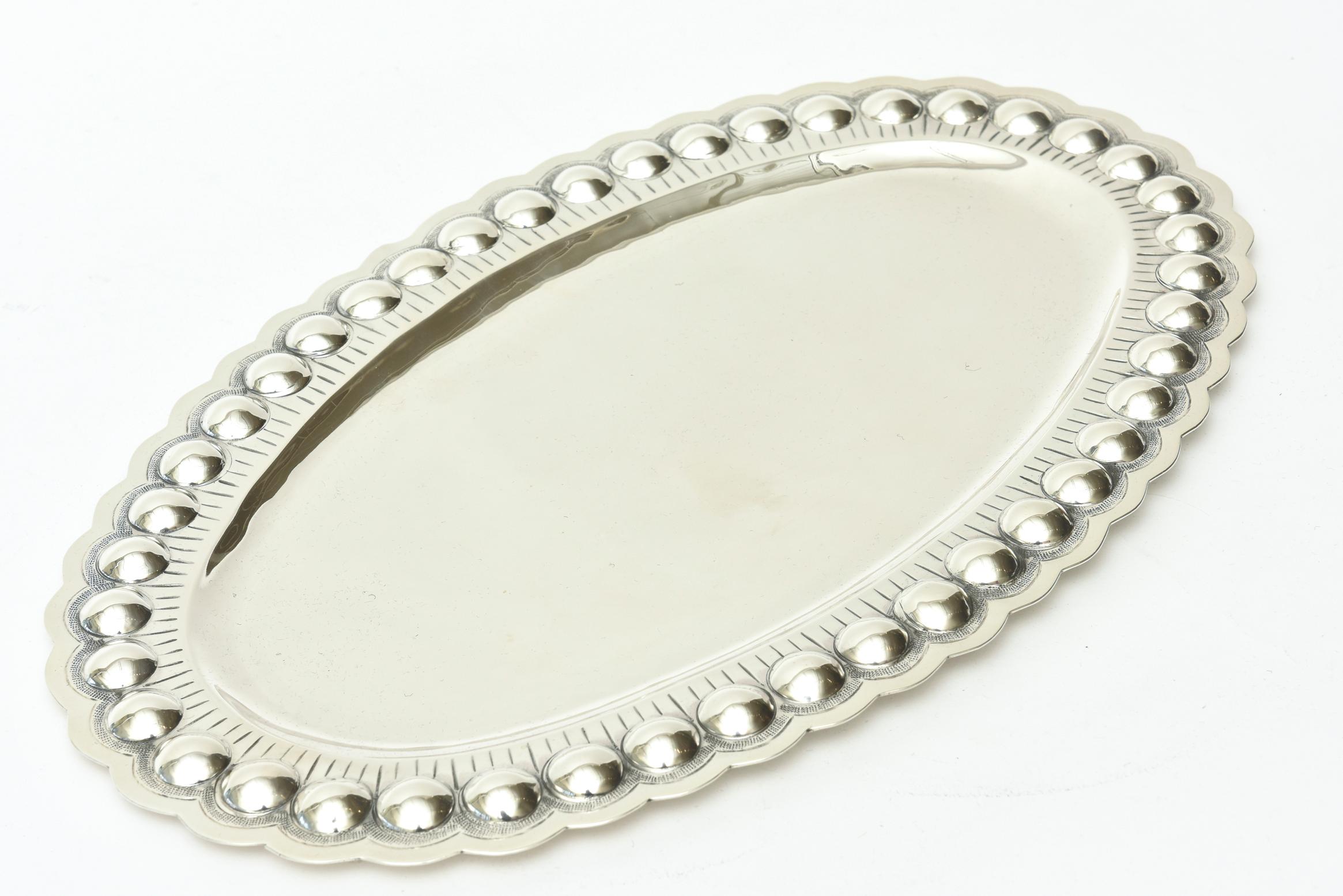 This lovely embellished Mid-Century Modern sterling silver tray is oval. The applications are varied for a multitude of uses as barware, serving and or holding towels for your bathroom. It is hallmarked 925, 1000 Sterling. It is from the 1950s and