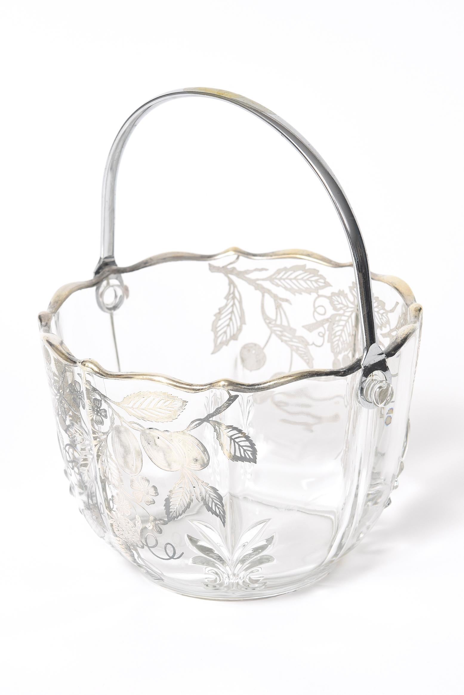 Lovely clear glass sterling silver overlay basket with leaf design in 4 areas along the bucket base. In two areas there are strawberries, grapes, cherries, leaves and flowers. The handle is chrome plated brass. Marked Sterling in the design. The