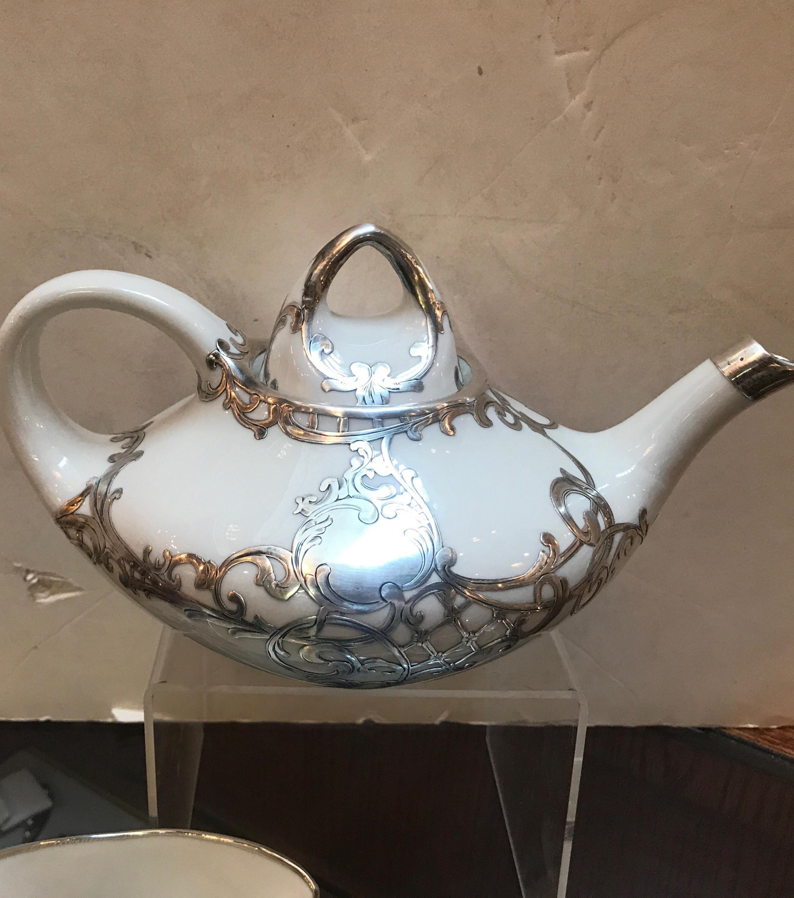 Beautiful 3-piece tea set with sterling silver overlay. The solid silver fused to the off white porcelain in excellent condition, The Aladdin shaped tea pot with an Art Nouveau style silver pattern overlay,
circa 1915-1920.