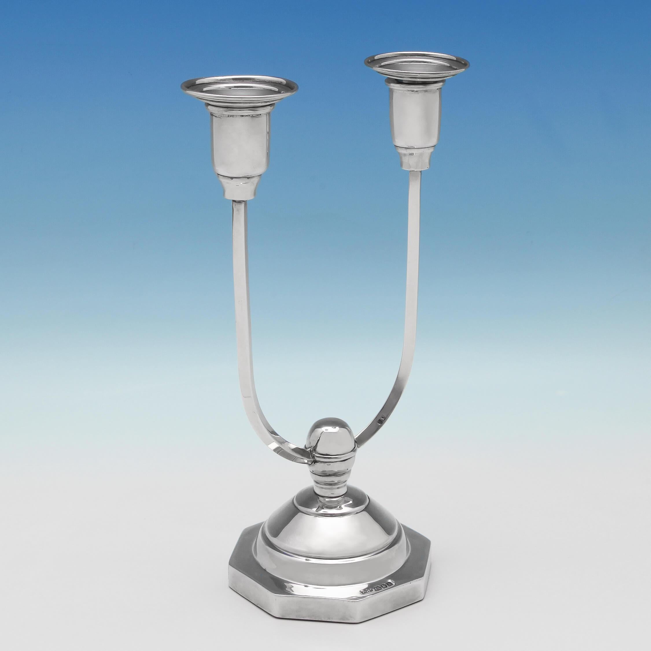 Hallmarked in London, 1946 by A. Taite & Sons, this unusual pair of George VI sterling silver Art Deco candelabra stand on filled, octagonal bases with u-shaped branches to hold two candles. They have removable sconces for ease of cleaning. The