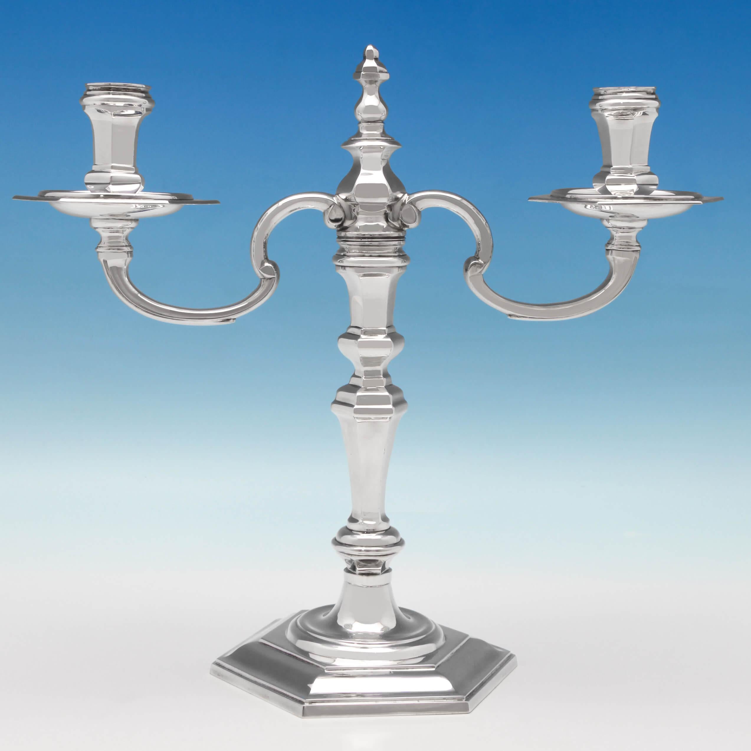 Hallmarked in London in 1988 by C. J. Vander, this handsome, pair of Elizabeth II, sterling silver candelabra, are cast, standing on hexagonal bases, and are reproductions of a George I style. Each candelabrum measures 10