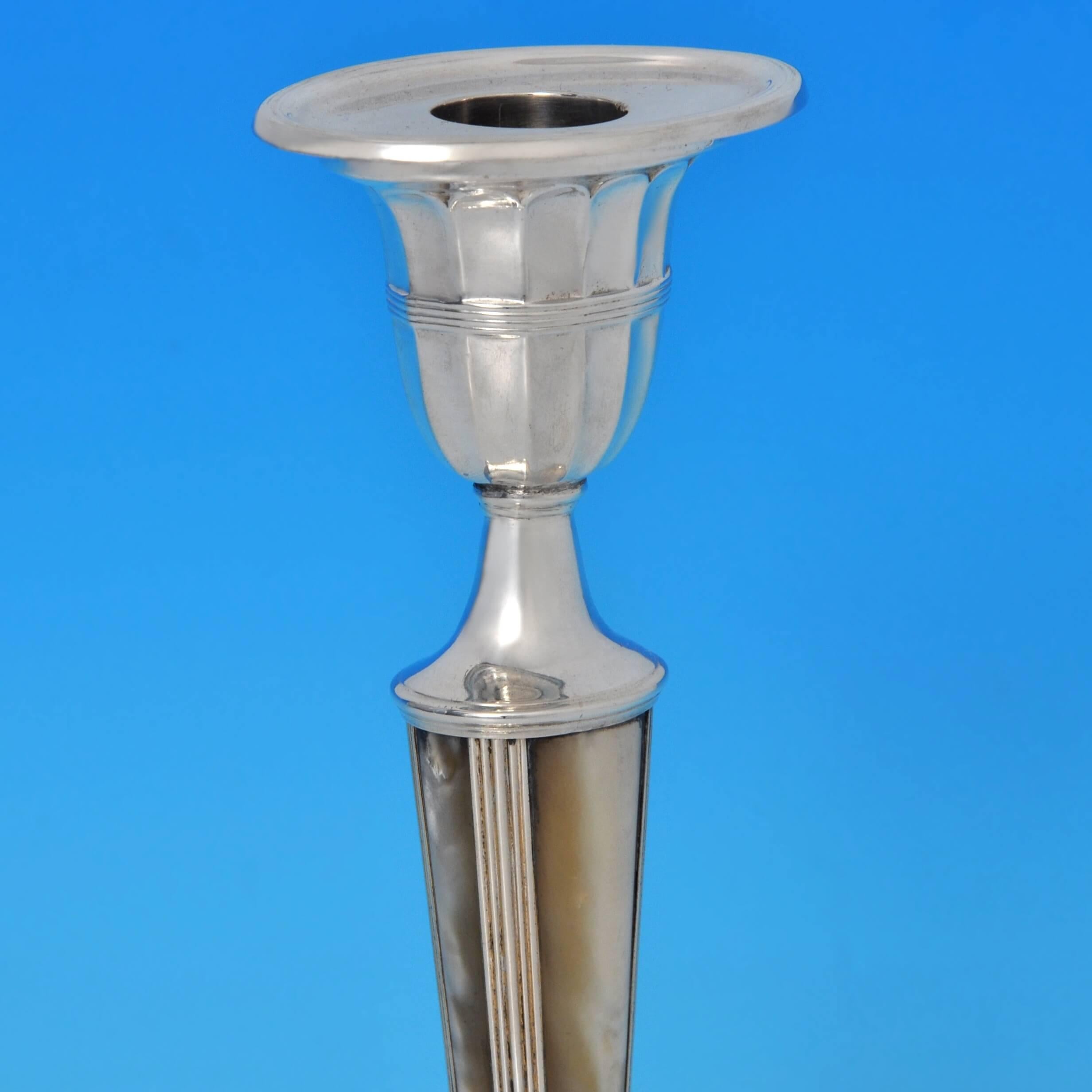 Hallmarked in Sheffield in 1904 by George Howson, this most unusual pair of antique, Edwardian, sterling silver candlesticks are oval in form and feature columns inlaid with vertical strips of mother of pearl, fluted bases and capitals and reeded
