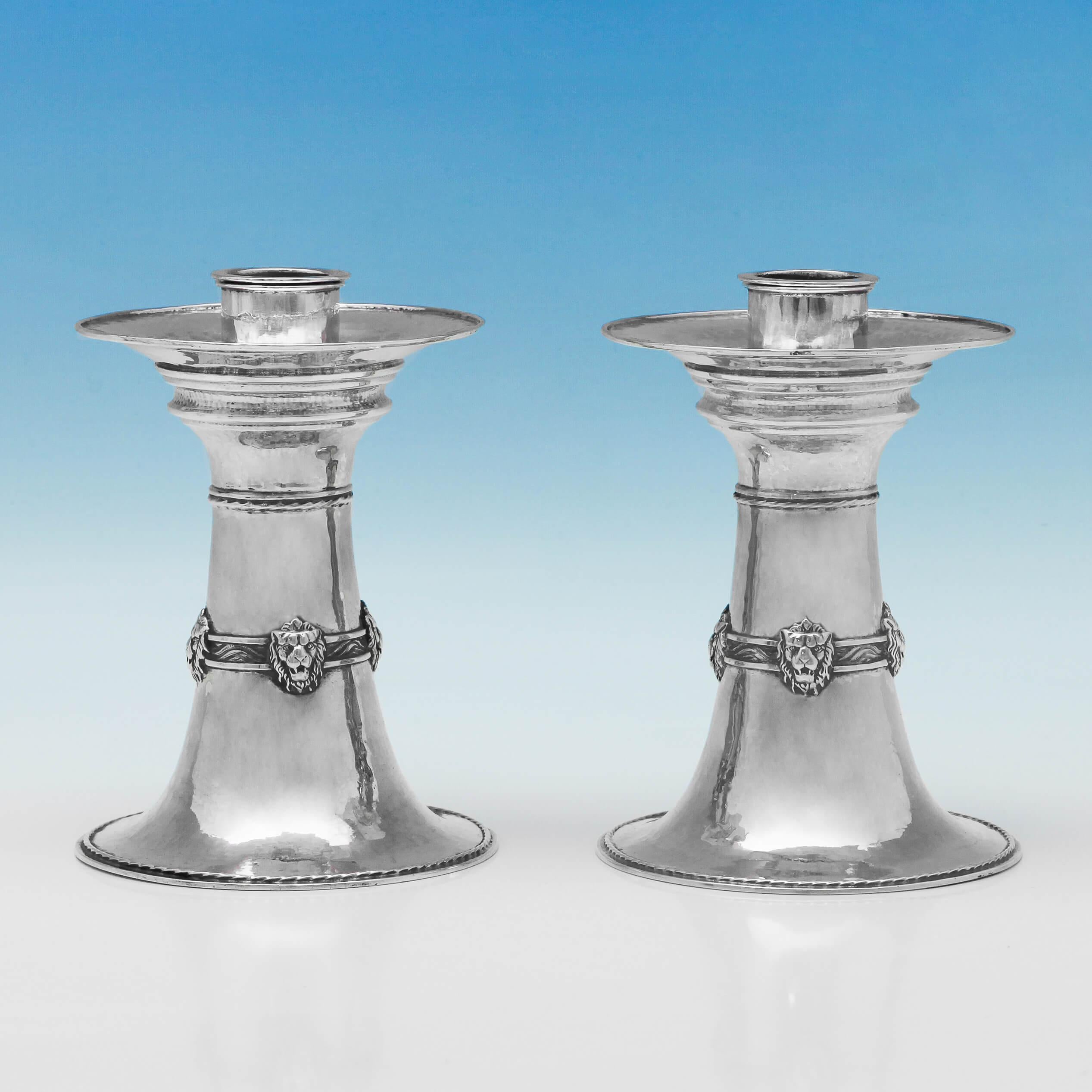 Hallmarked in London in 1924 by Omar Ramsden, this magnificent pair of sterling silver candlesticks, have a hand-hammered finish, and feature lion mask decoration and rope detailing. The base of each candlestick is engraved “Omar Ramsden Me Fecit”.
