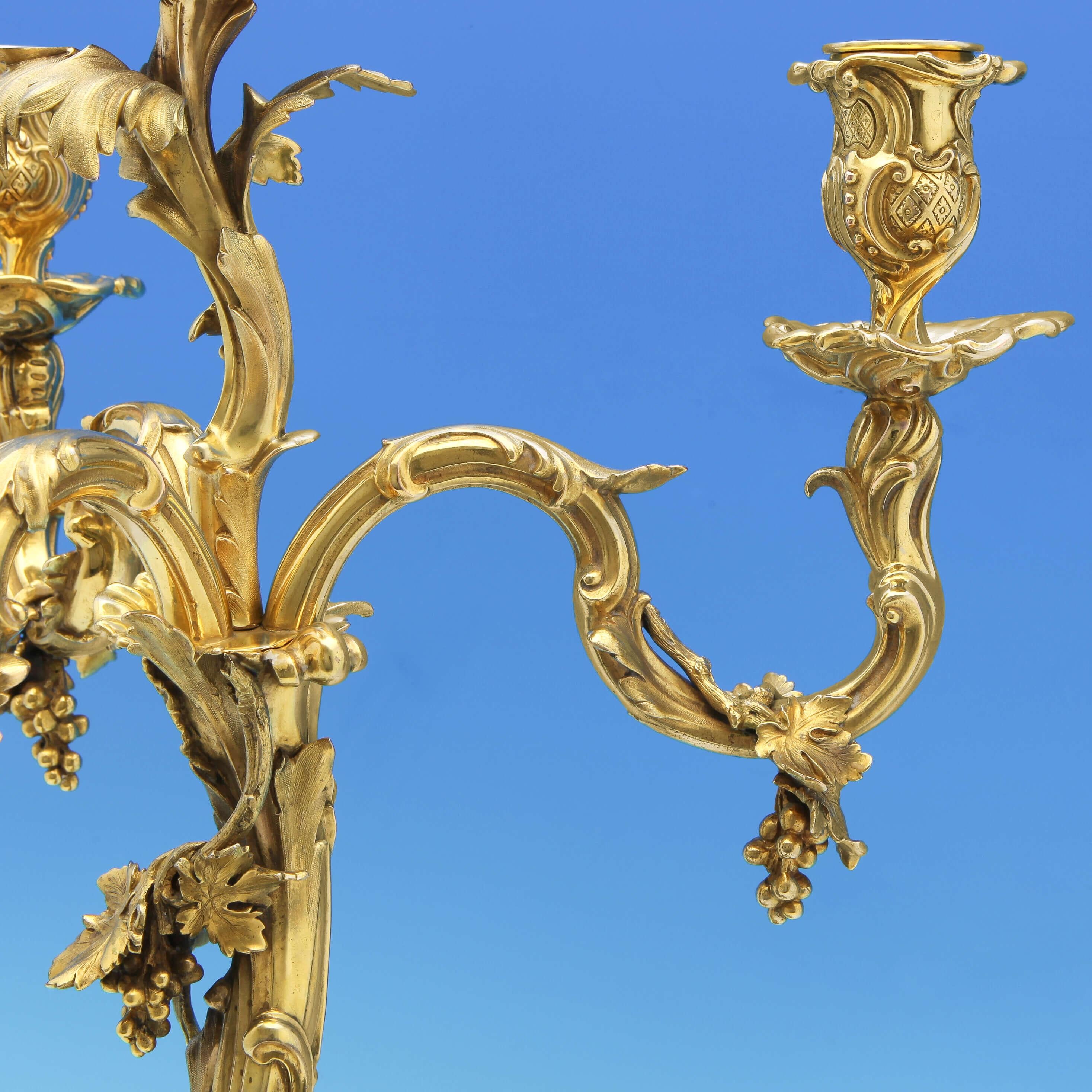 This fantastic pair of antique, Victorian, silver gilt candelabra were made in London in 1867 and 1890 by Hunt & Roskell and Benson & Webb respectively. Benson & Webb purchased Hunt & Roskell in 1889. They feature grape and vine decoration to the