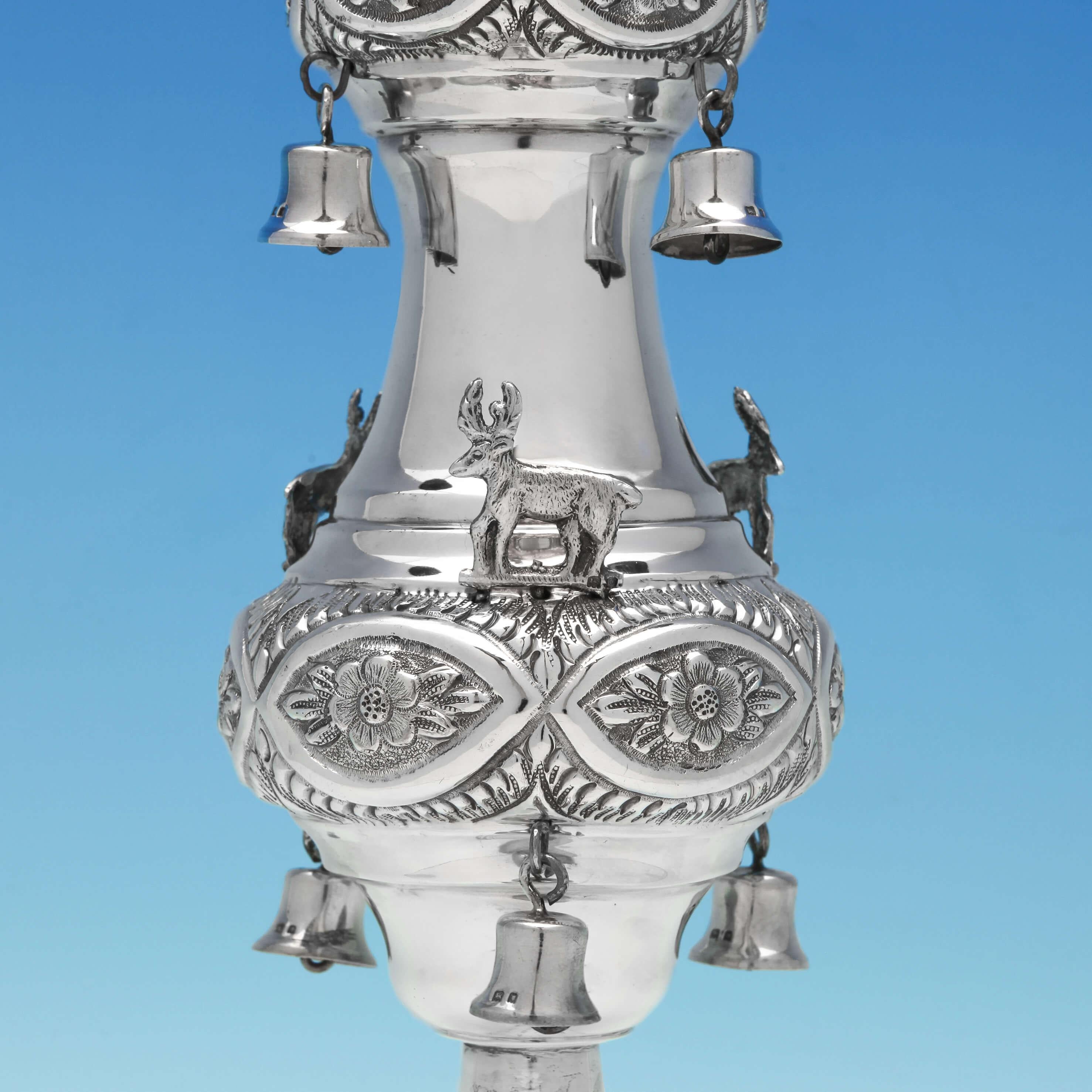 Hallmarked in London in 1920 by Maurice Salkind, this impressive pair of sterling silver Rimonim feature floral chasing, eagle finials, deer, hanging bells and beaded bases. The handles have been engraved with Hebrew script. Each Rimonim stands