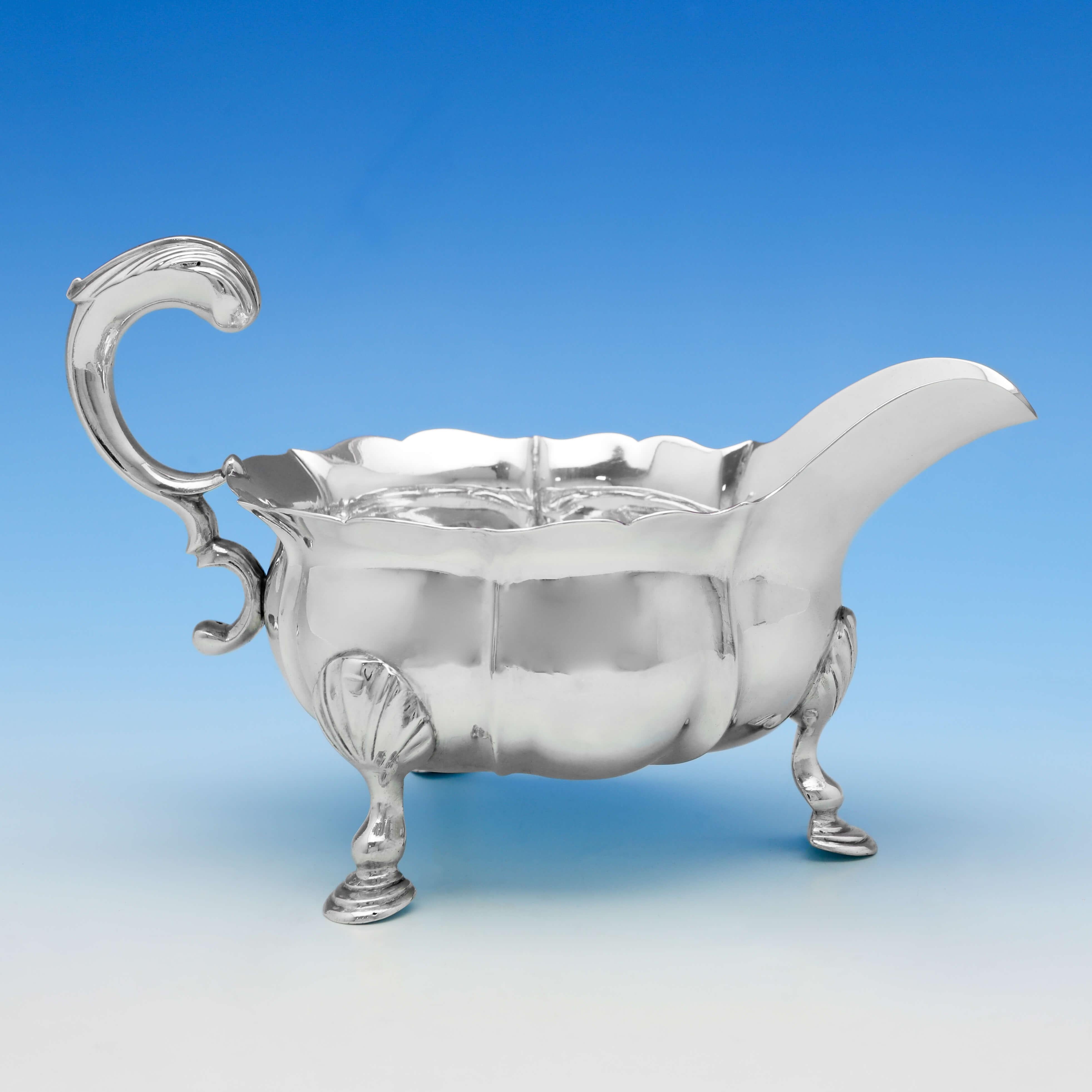Hallmarked in London in 1749 by John Pollock, this striking pair of George II, antique sterling silver sauce boats, feature shaped borders and sides, acanthus detailed handles, and stand on three feet. Each sauce boat measures 5