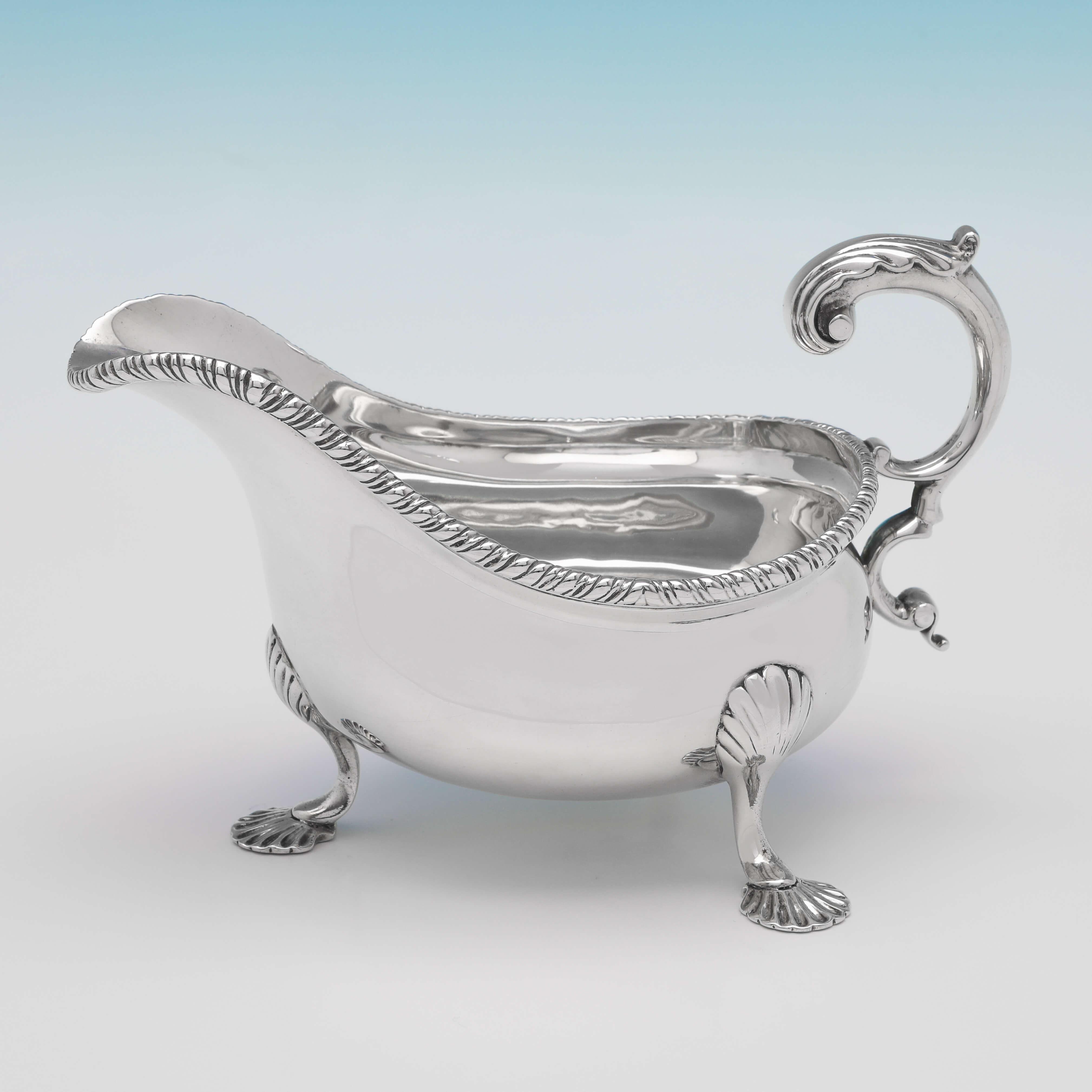 Hallmarked in London in 1896 by Lambert & Co., this handsome, pair of Victorian, Antique Sterling Silver Sauce Boats, feature gadroon borders, acanthus detailed flying C-scroll handles, and stand on three feet. Each sauce boat measures 4.25
