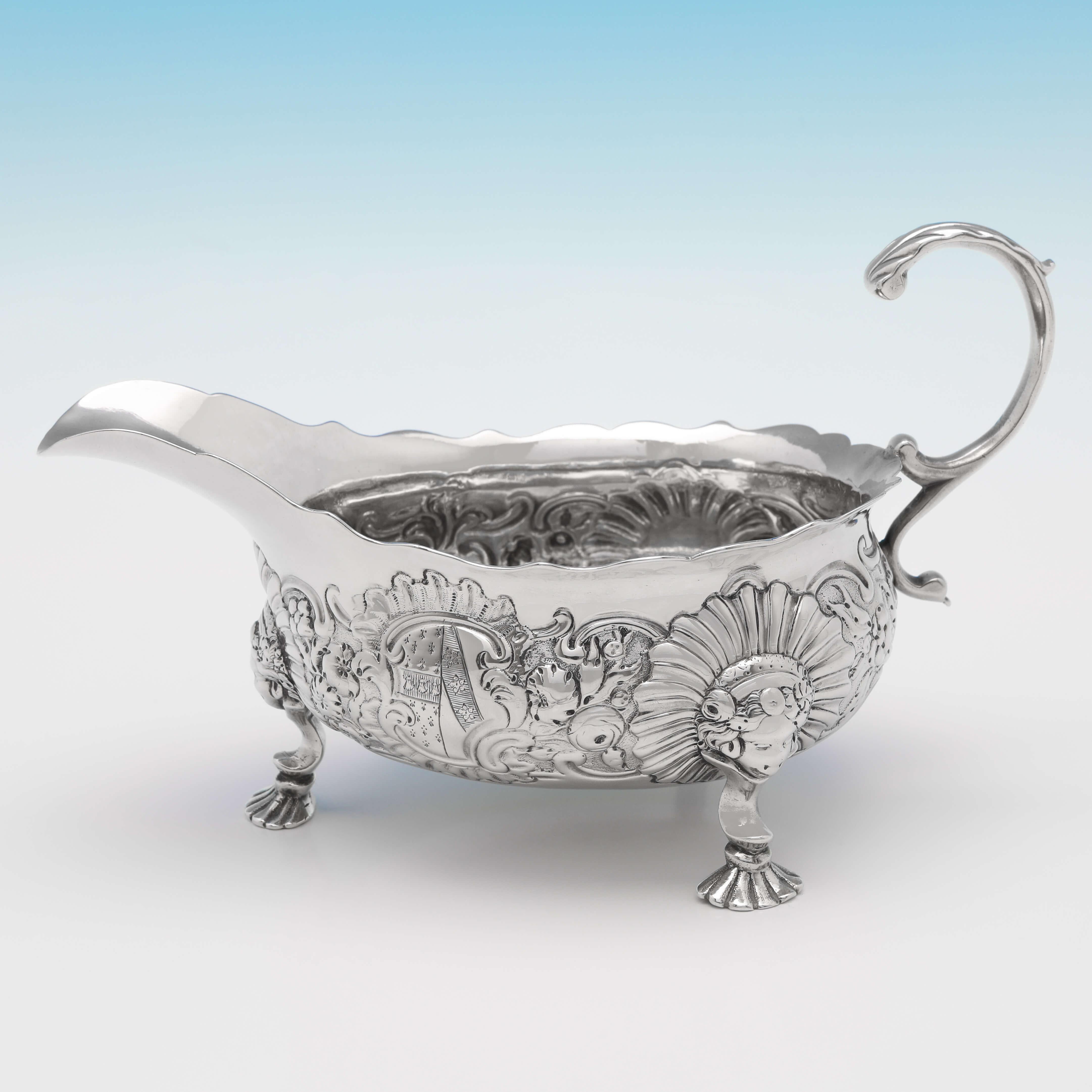 Hallmarked in London in 1746 by Richard Kersill, this striking pair of George II, antique sterling silver sauce boats, feature Rococo chasing to the bodies, three feet with shell and mask decoration, and acanthus detailed flying C-scroll handles.