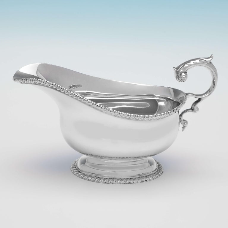 Hallmarked in London in 1939 by R. W. Blenkinsop, this handsome pair of Sterling Silver Sauce Boats, stand on pedestal feet, and feature gadroon borders, and acanthus detailed flying C scroll handles. Each sauce boat measures 4.25