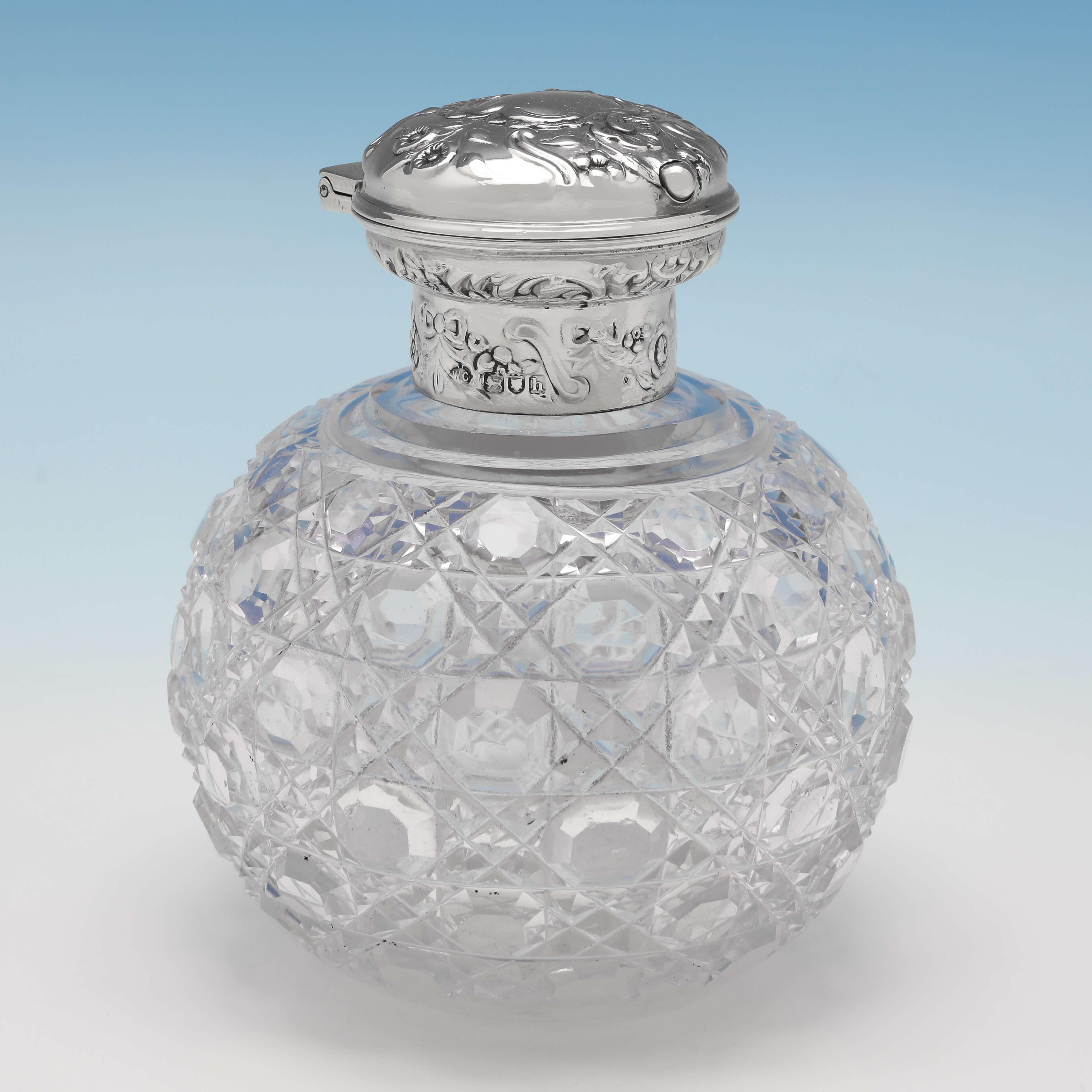Hallmarked in London in 1903 by William Comyns, this very attractive pair of Antique Sterling Silver Scent Bottles, feature traditional cut glass bodies, and ornate lids which open via push buttons. Each scent bottle measures 4.75