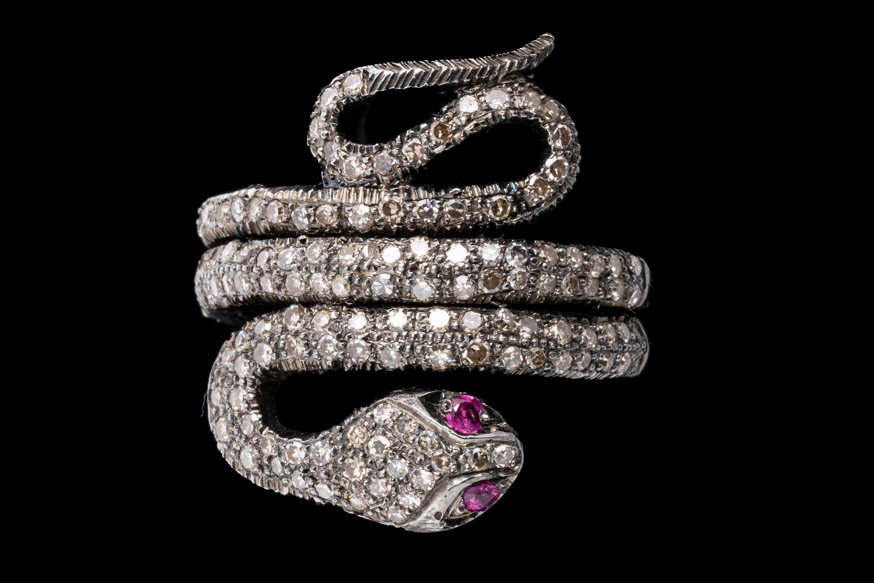 Sterling silver ring. This stunning ring is a slithering and coiled snake motif with a pave set, round faceted diamond set body, approximately 0.66 TCW, which has a double coil that acts as the shank, finished by synthetic ruby eyes.
Marks: None,