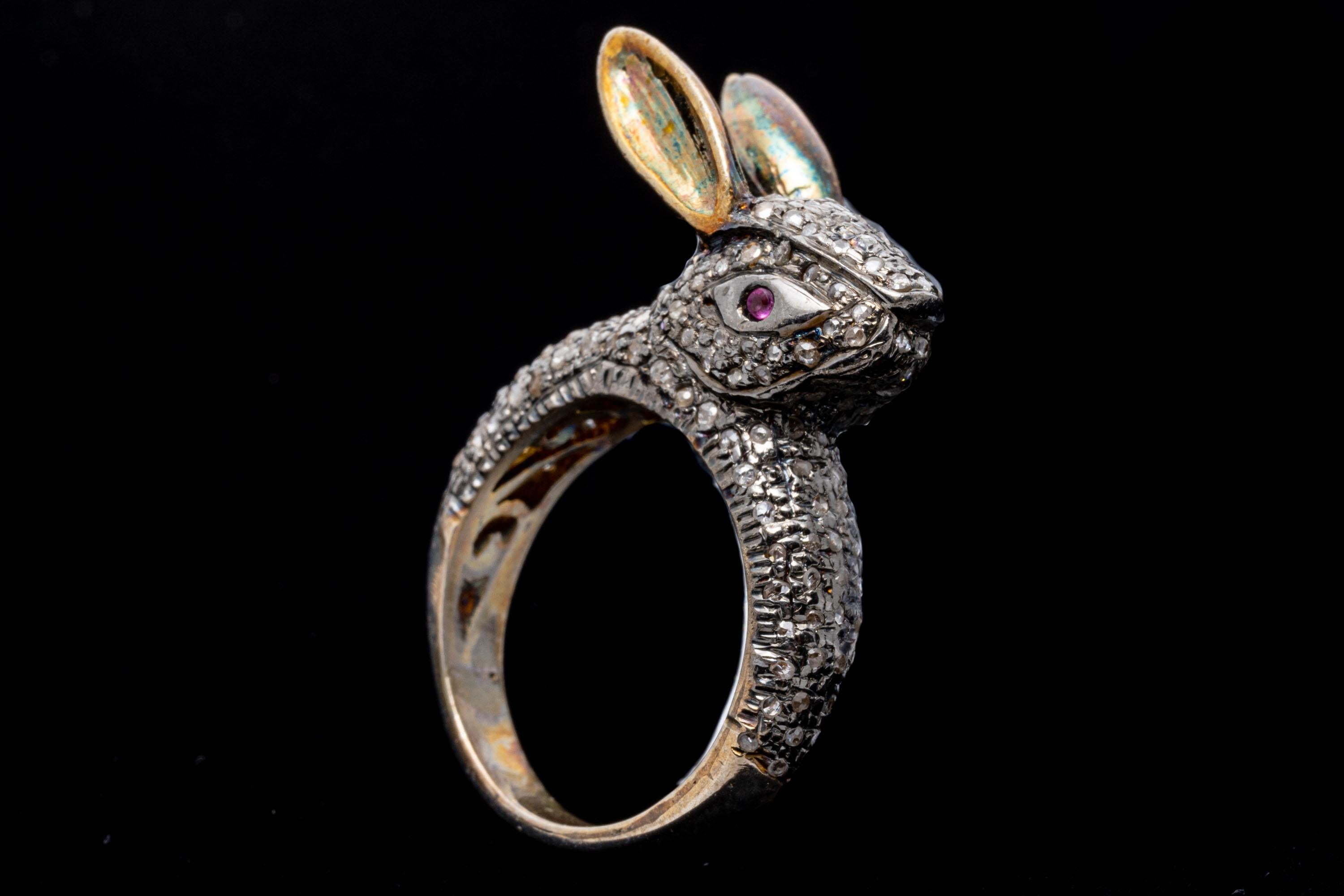 Sterling silver ring. This striking ring is a charming bunny head, and set in the entirety with pave set, round rose cut faceted diamonds, approximately 0.48 TCW and decorated with highlighted yellow vermeil ears. Round faceted, pinkish red rubies,