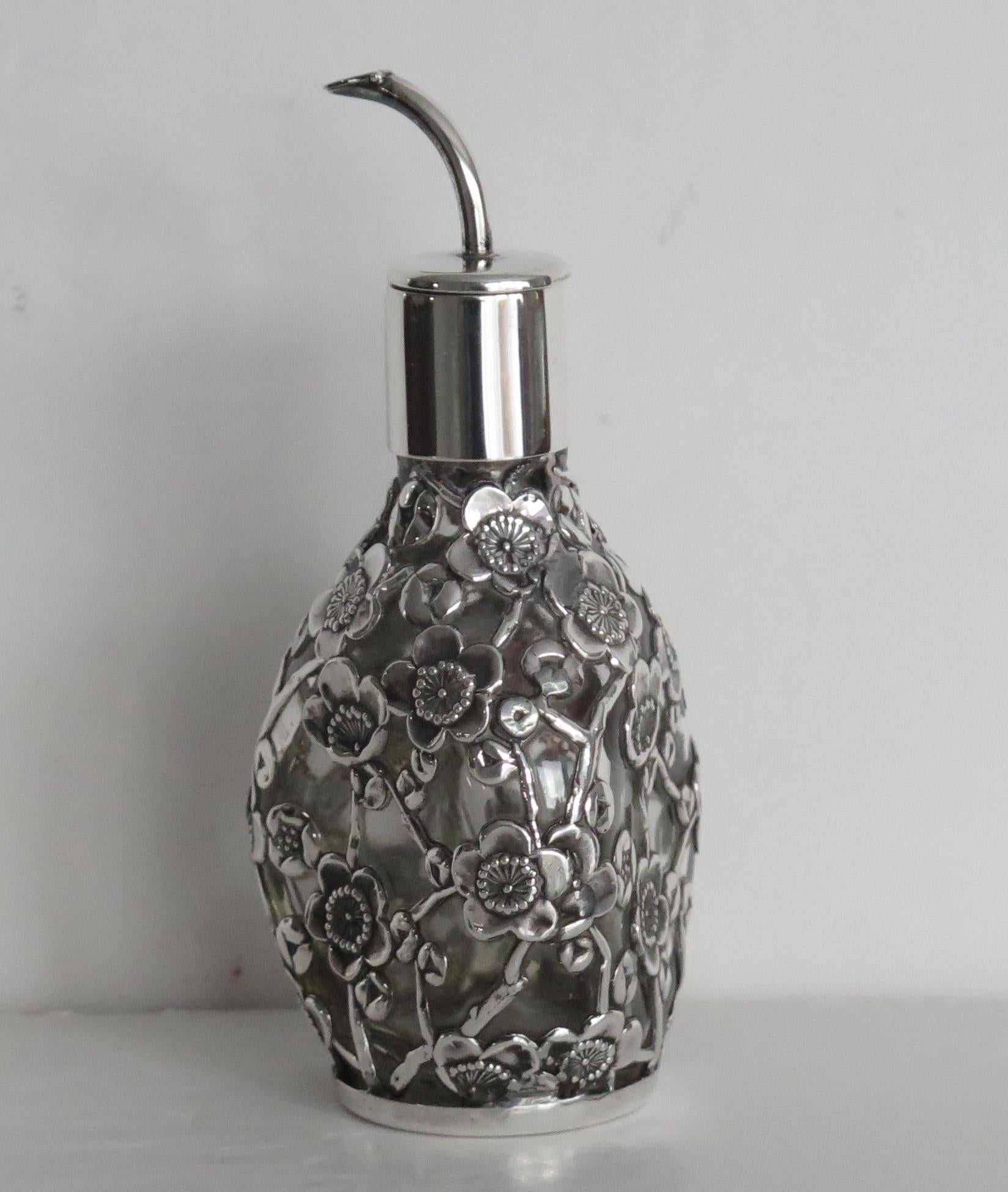 This is a high quality sterling silver cased glass perfume or scent bottle, made in Edwardian England, Circa 1900 to 1910

The pressed glass bottle has a triangular shape with curved sides. The bottle is encased with a sterling silver filigree case