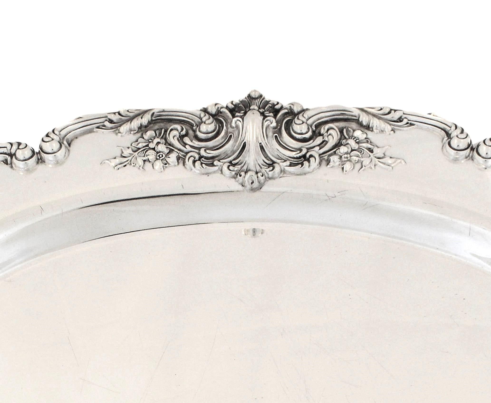 Se ofrece una fuente (bandeja) de plata de ley de Redlich & CO de Nueva York.  Es una gran bandeja de servir con detalles del viejo mundo en los bordes.  Tiene un borde festoneado con flores que decoran el borde.  El interior es completamente plano