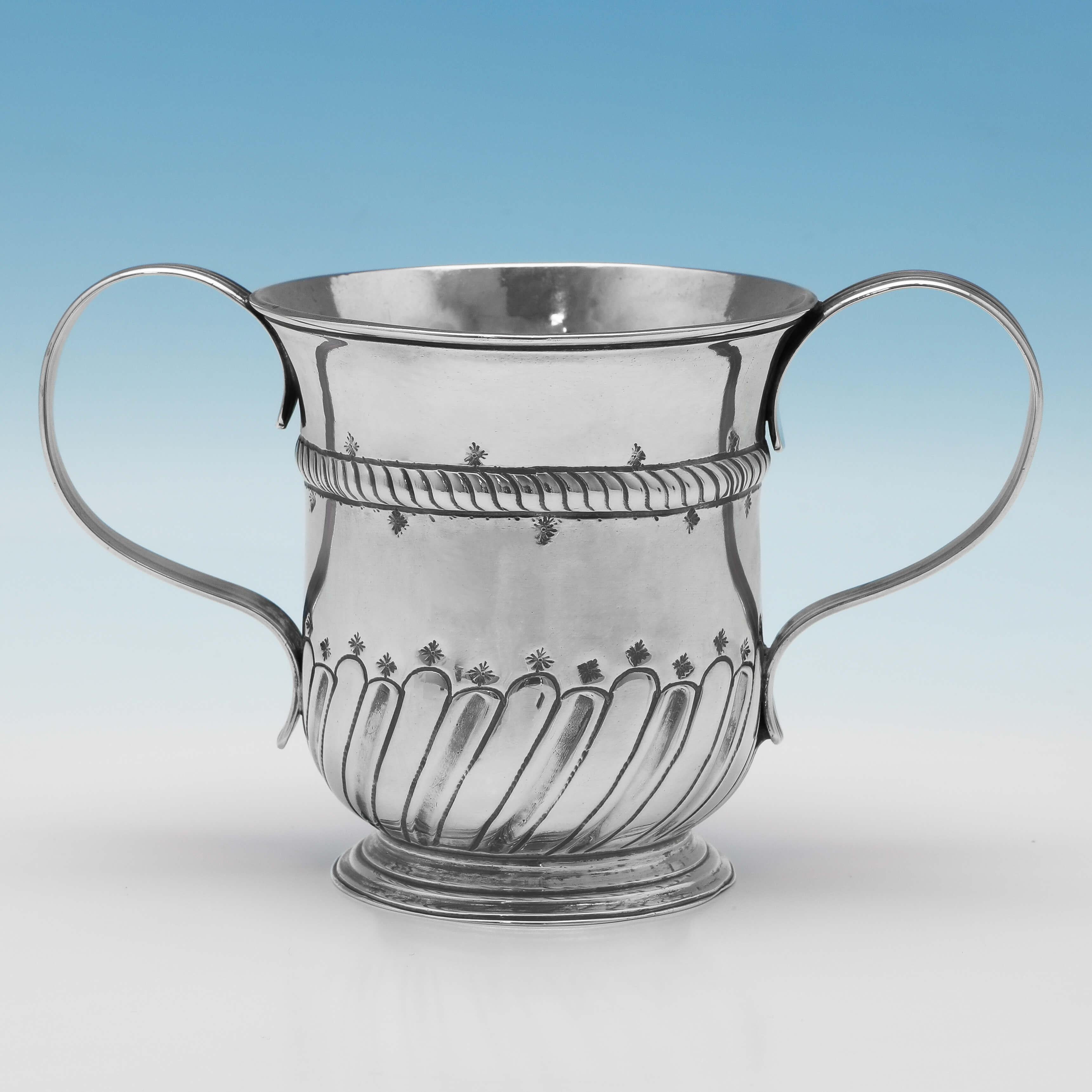 Hallmarked in London in 1756 by William Shaw II & William Preist, this George II, antique sterling silver porringer, is of a traditional form, featuring reed detailed handles and chased decoration to the body. The porringer measures 4