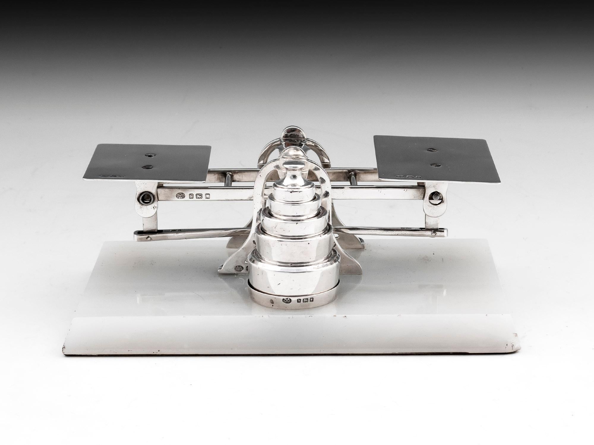 Antique sterling silver postal scales by famous London Silversmith George Betjemann & Sons complete with graduated silver weights. Stands on a solid white onyx base.
