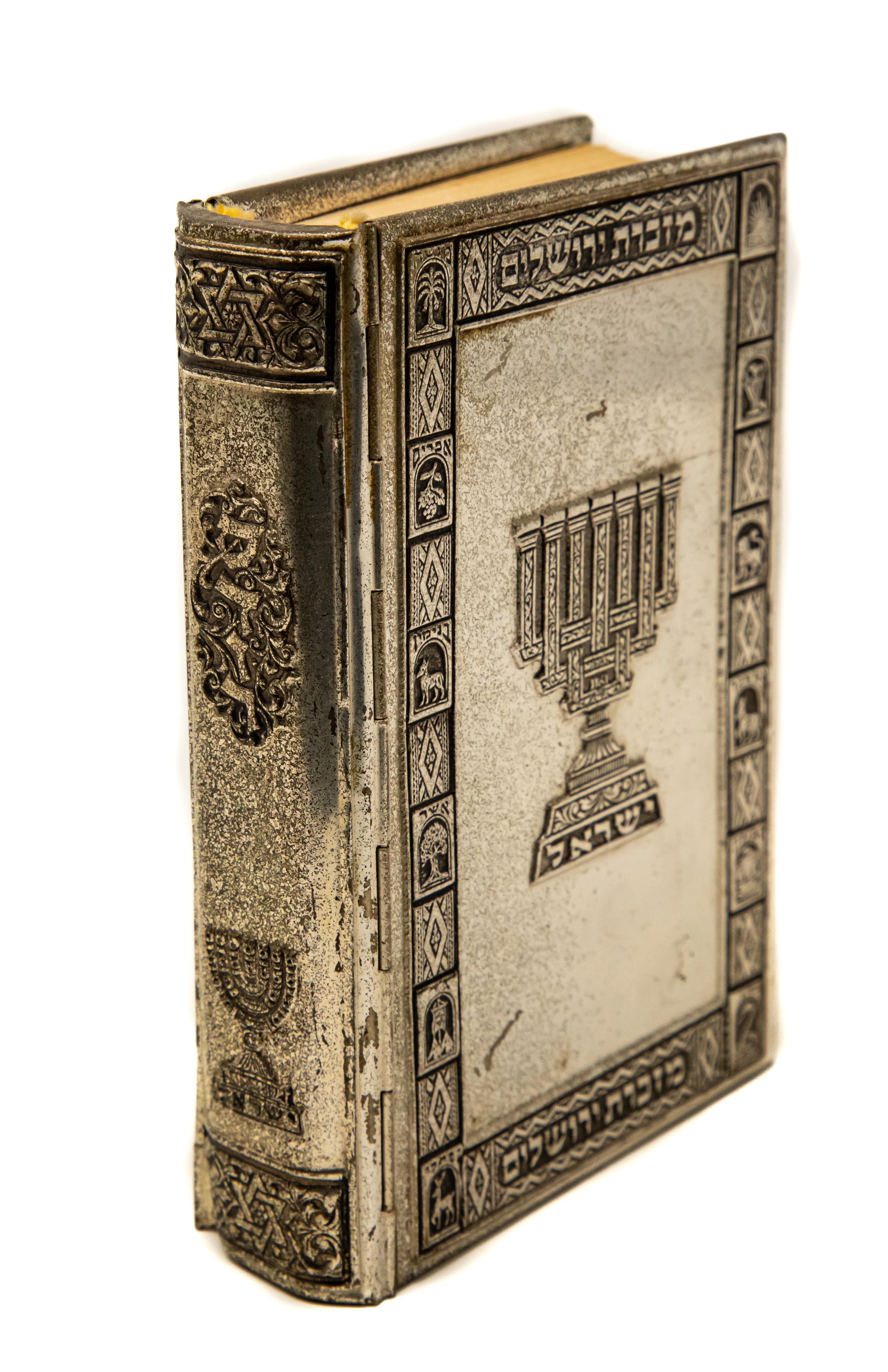 Offering this magnificent sterling silver prayer book. The book is in English and Islam. The cover is sterling silver with filigree. One side has a crown that is over two arched tablets. The other side depicts a menorah. A metal-bound Jewish prayer