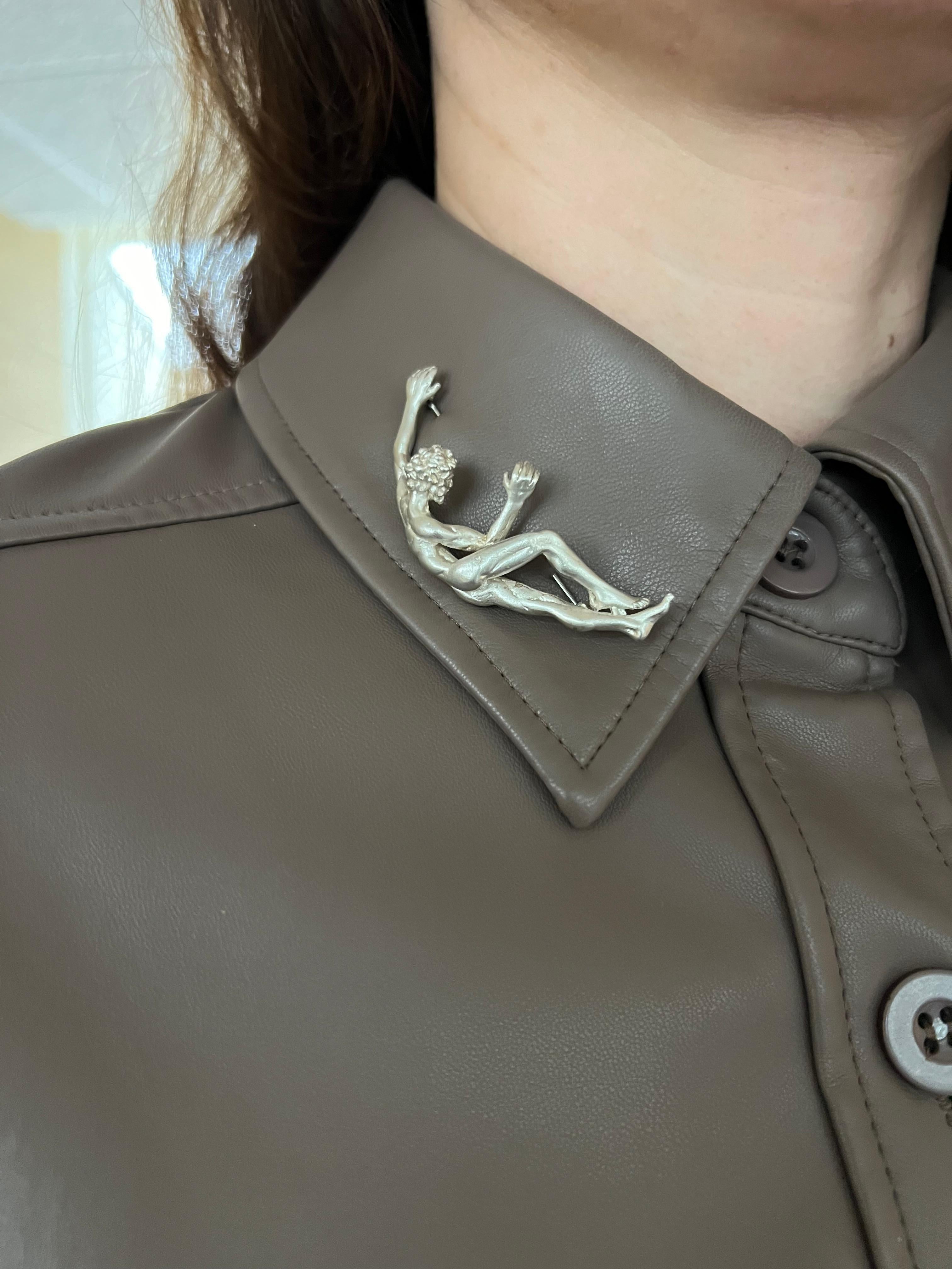 Elaborado con exquisita atención al detalle, este alfiler de plata de ley representa la serena elegancia de un hombre recostado, capturado en un momento de tranquilo reposo. La forma de la figura está esculpida con delicadeza, y cada curva y