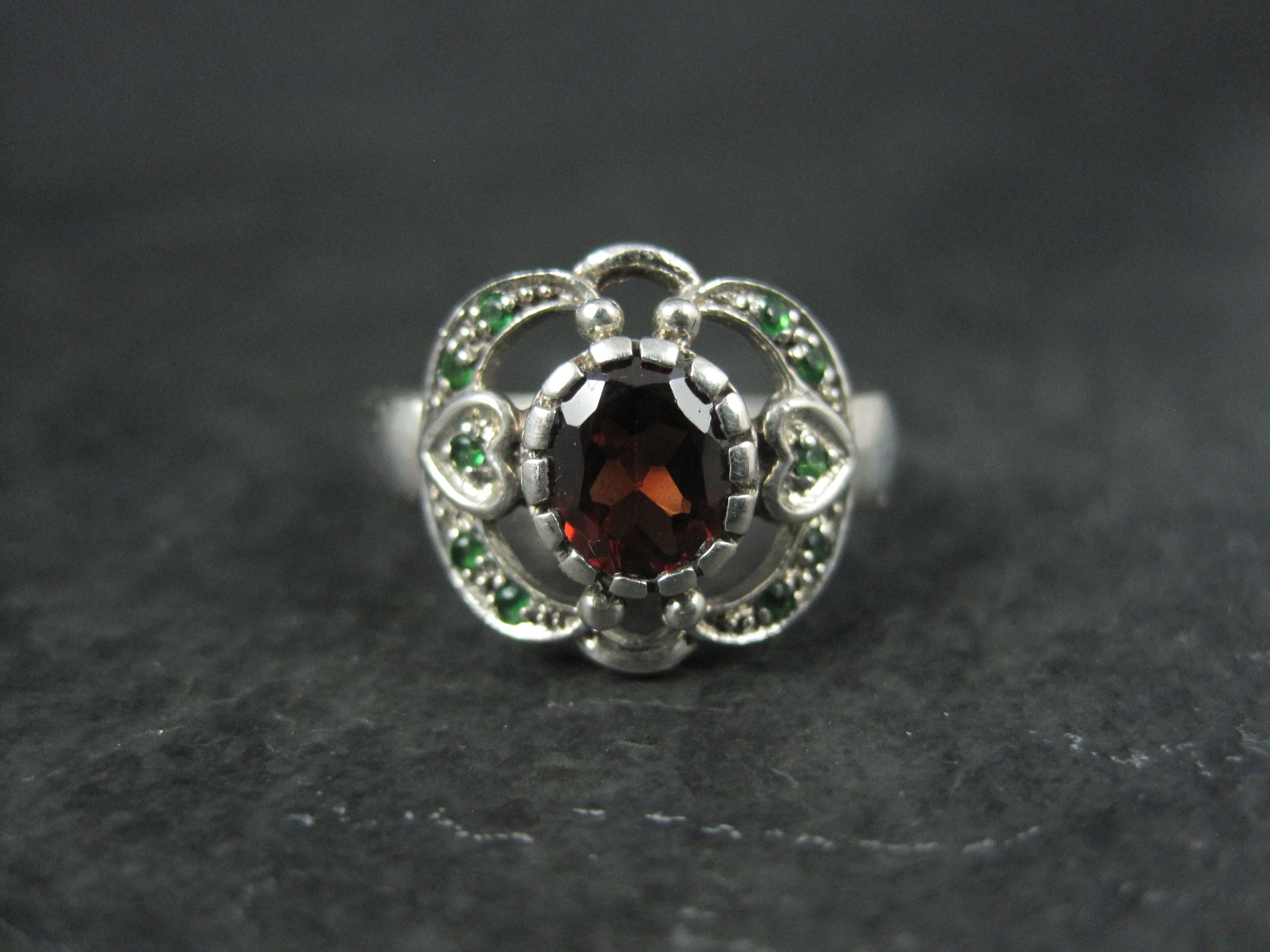 This gorgeous ring is sterling silver.
It features a 6x7mm red garnet accented by tiny tsavorite garnets.
The face of this ring measures 1/2 of an inch north to south.
Size: 5.5
Marks: 925
Condition: Excellent